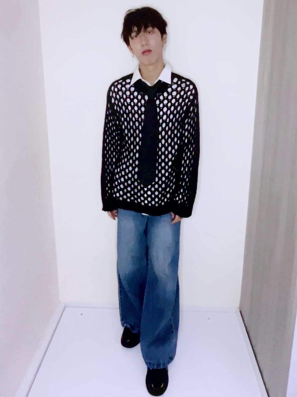 ブルー系のデニムパンツ、ブラック系のスニーカー、ブラック系のニット/セーターを着用したメンズの秋コーディネートの3枚目の写真