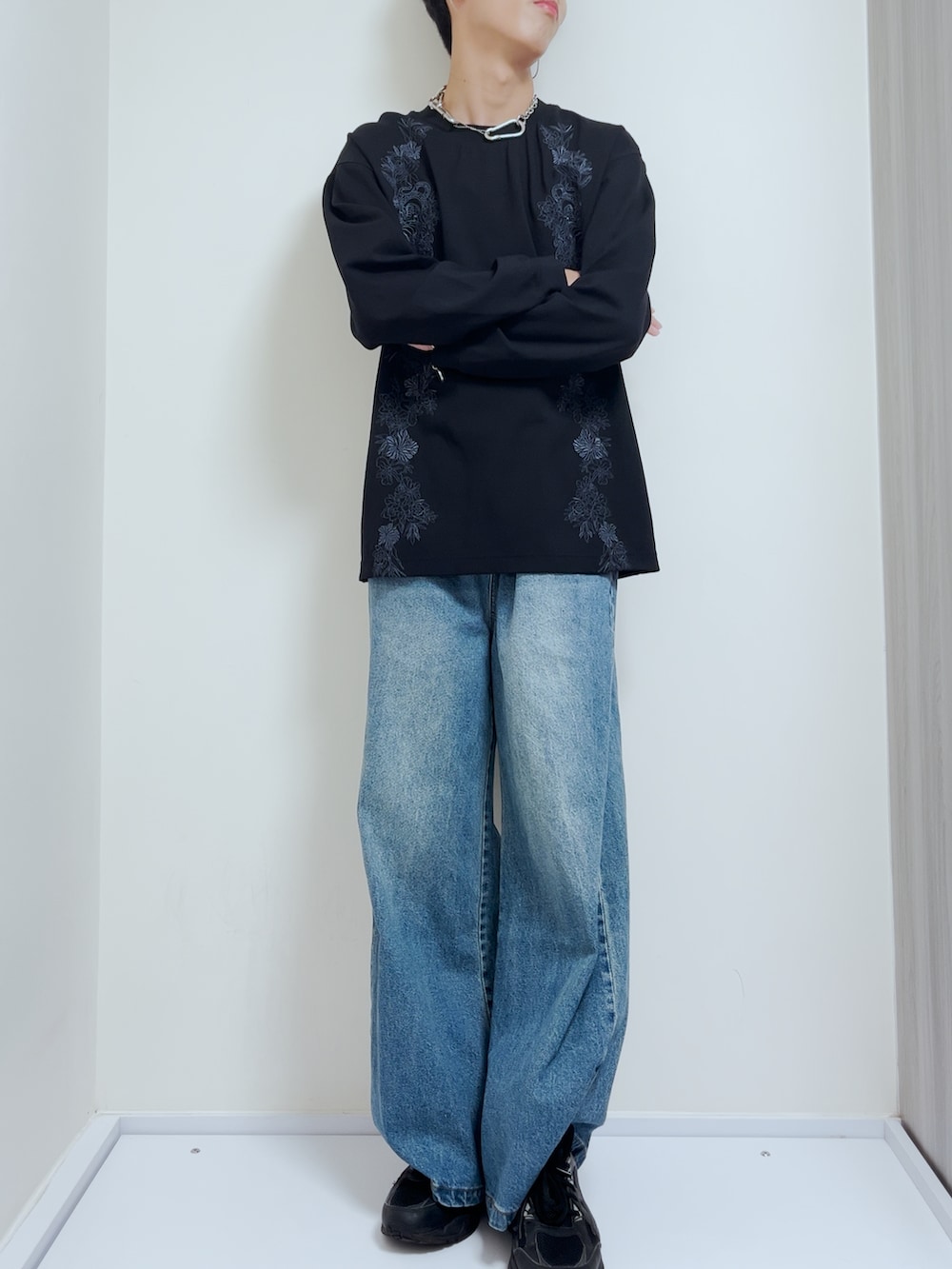 ブルー系のデニムパンツ、ブラック系のニット/セーター、ブラック系のスニーカーを着用したメンズの秋コーディネートの2枚目の写真