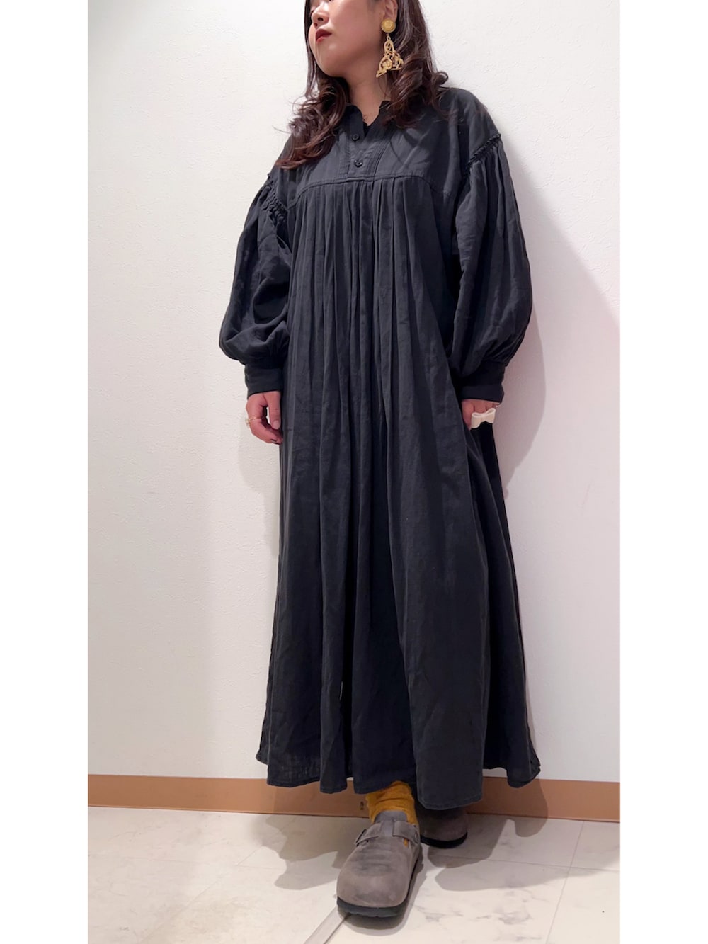 ホワイト系のカーディガン/ボレロ、ブラック系のワンピース、グレー系のサンダルを着用したレディースの秋コーディネートの2枚目の写真