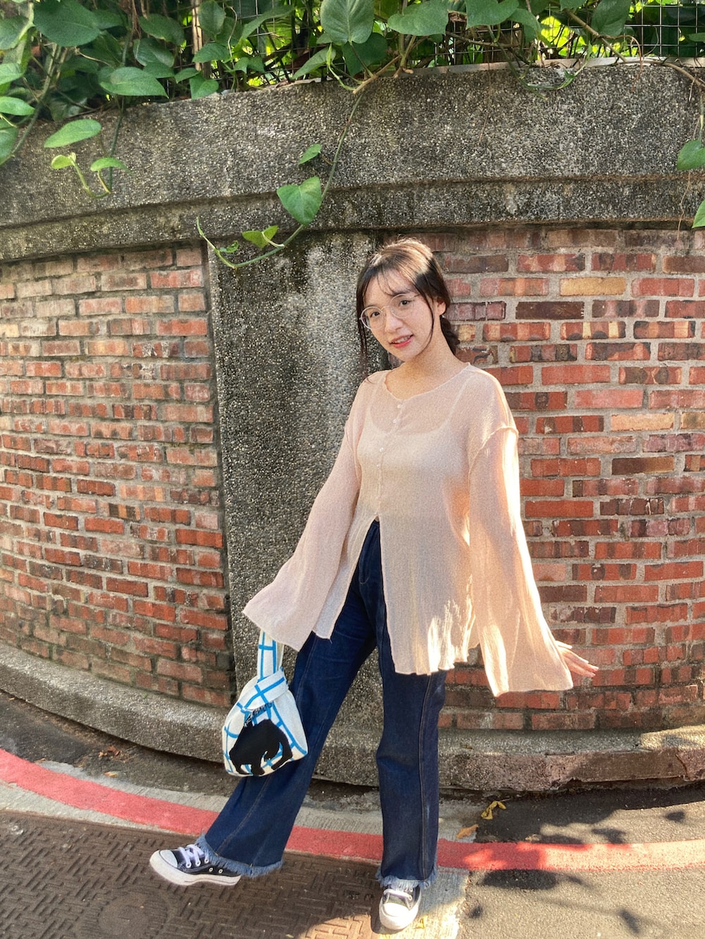 ブルー系のデニムパンツ、ベージュ系のトップス、ブラック系のスニーカーを着用したレディースの秋コーディネートの2枚目の写真