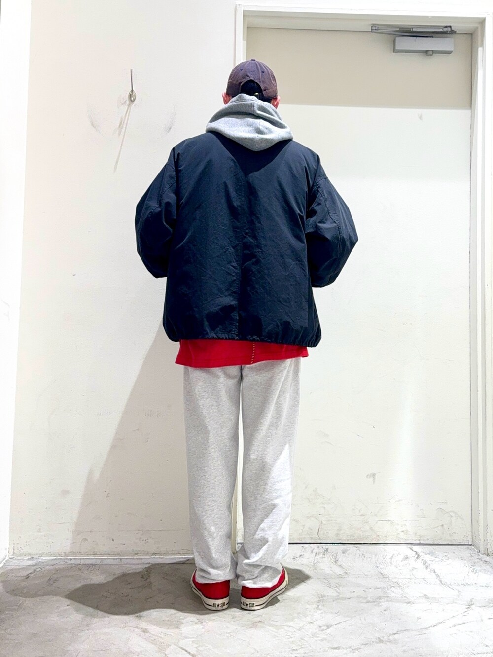 グレー系のパーカー、ブラック系のモッズコート、レッド系のTシャツ/カットソーを着用したメンズの秋コーディネートの4枚目の写真