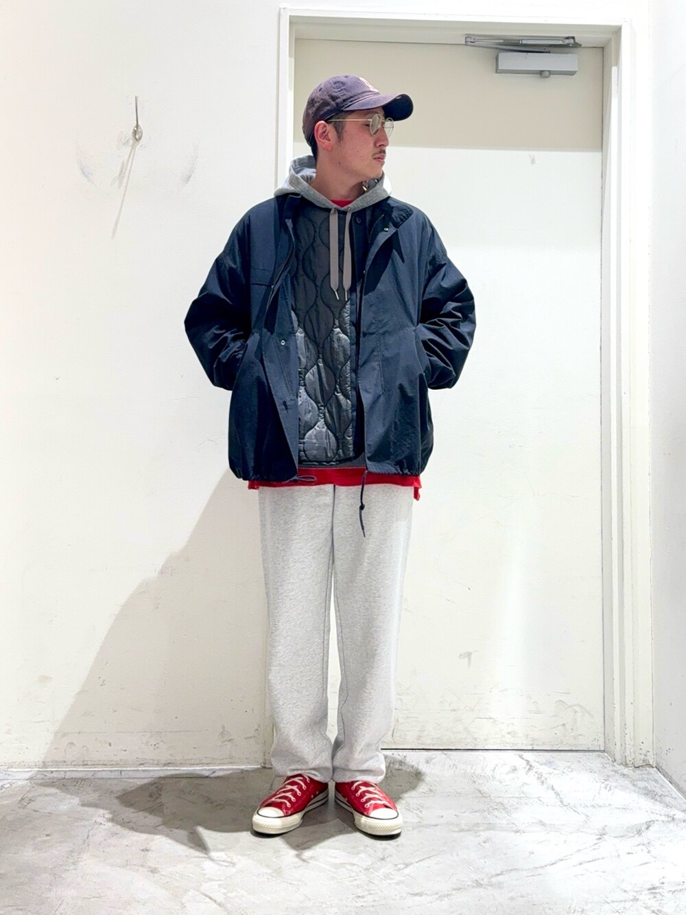 グレー系のパーカー、ブラック系のモッズコート、レッド系のTシャツ/カットソーを着用したメンズの秋コーディネートの2枚目の写真