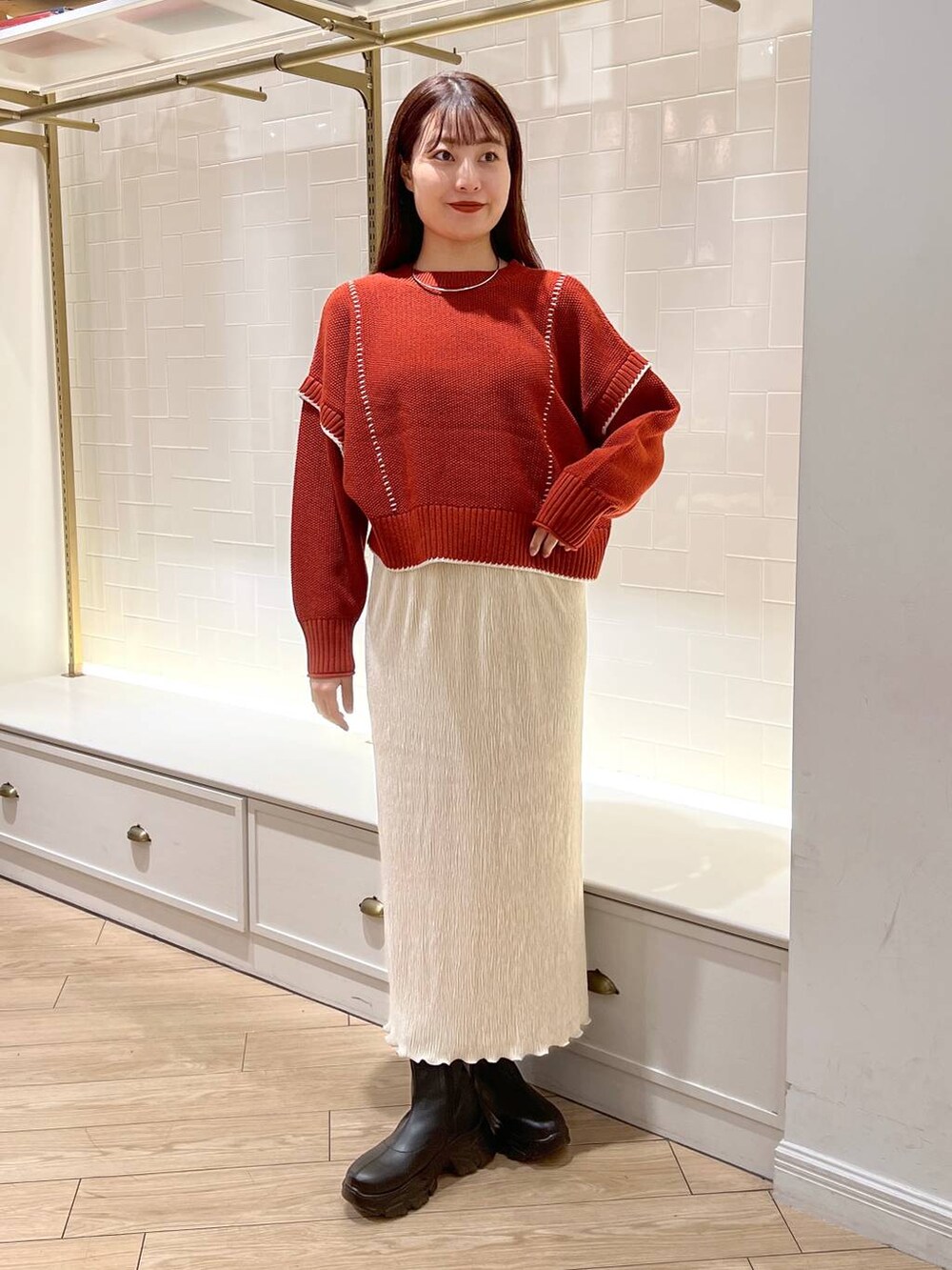 ブラック系のブーツ、レッド系のニット/セーター、ホワイト系のスカートを着用したレディースの秋コーディネートの3枚目の写真