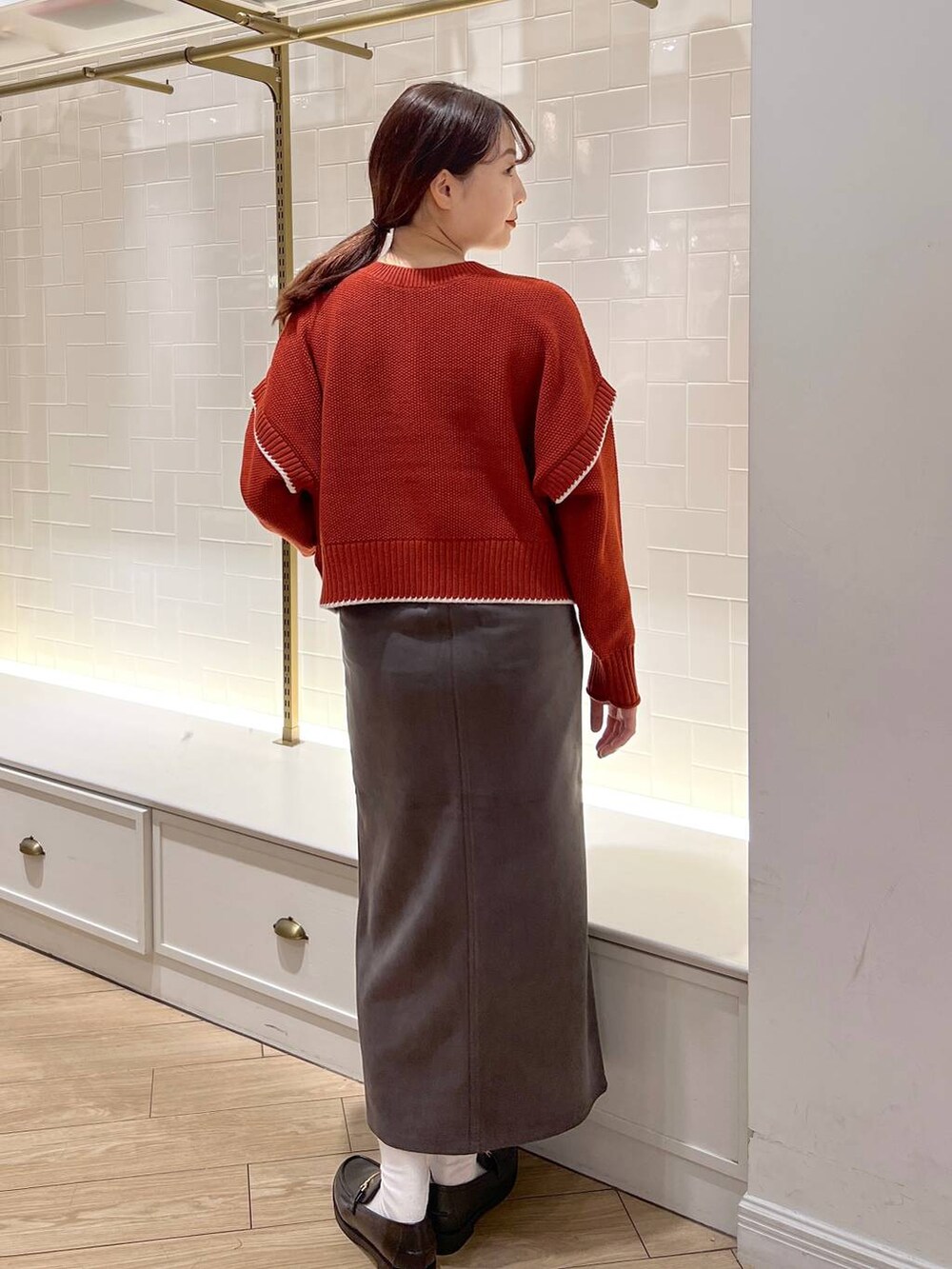 レッド系のニット/セーター、グレー系のスカート、ブラック系のローファーを着用したレディースの秋コーディネートの3枚目の写真