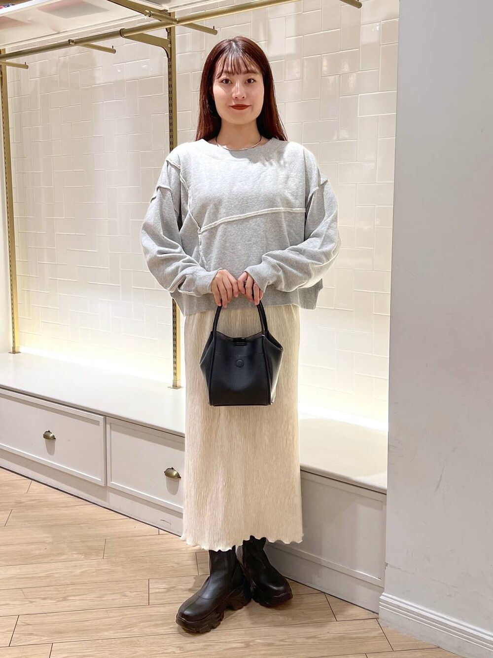 ブラック系のブーツ、グレー系のスウェット、ブラック系のショルダーバッグを着用したレディースの秋コーディネートの2枚目の写真