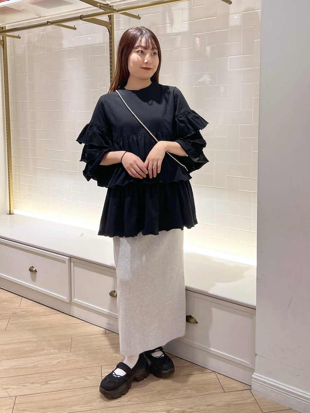 グレー系のスカート、ブラック系のスニーカー、ブラック系のワンピースを着用したレディースの秋コーディネートの2枚目の写真