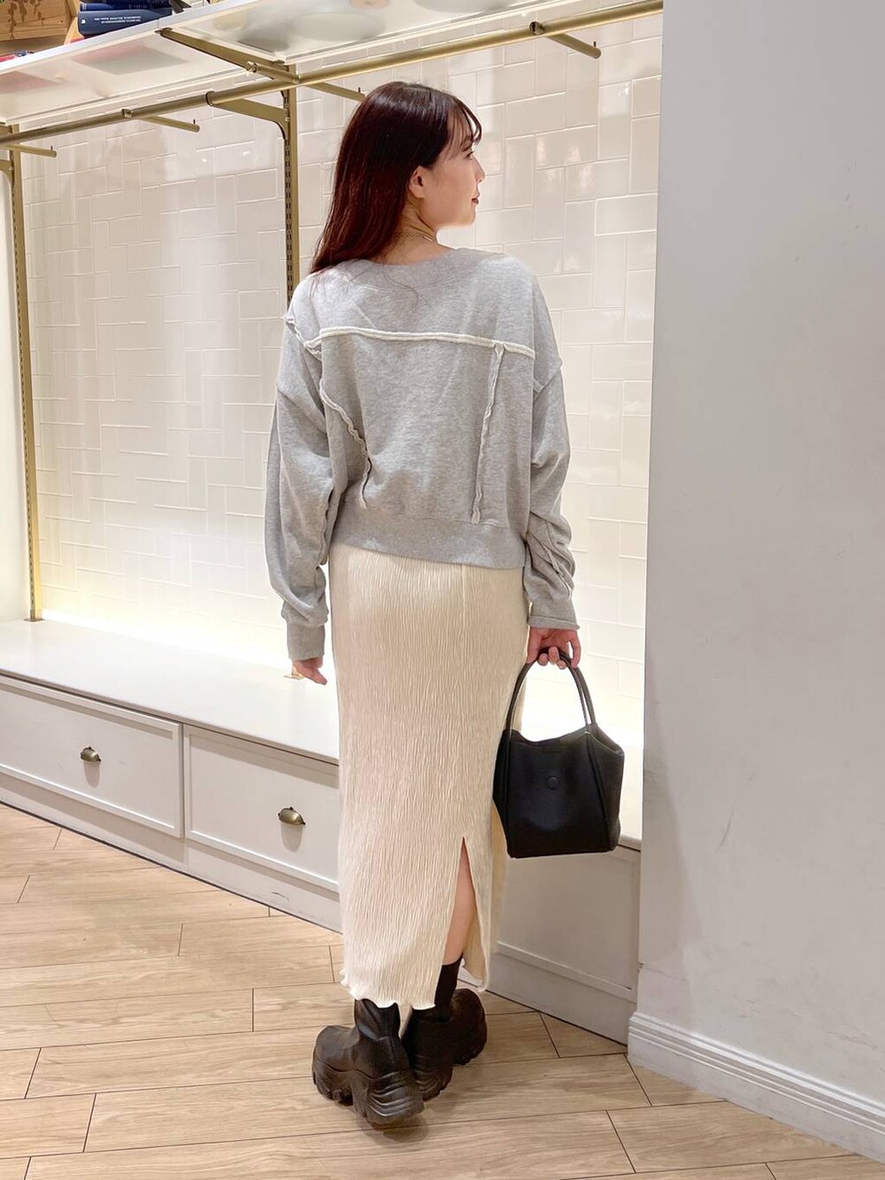 ブラック系のブーツ、グレー系のスウェット、ブラック系のショルダーバッグを着用したレディースの秋コーディネートの4枚目の写真