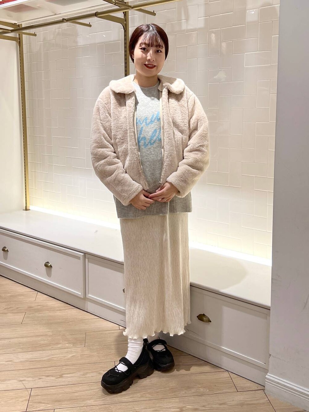 ホワイト系のブルゾン、ブラック系のスニーカー、ホワイト系のスカートを着用したレディースの秋コーディネートの2枚目の写真