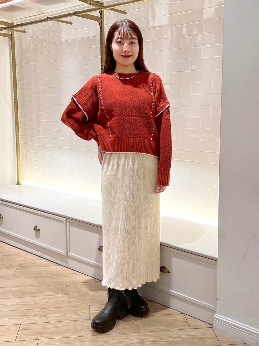 ブラック系のブーツ、レッド系のニット/セーター、ホワイト系のスカートを着用したレディースの秋コーディネートの2枚目の写真