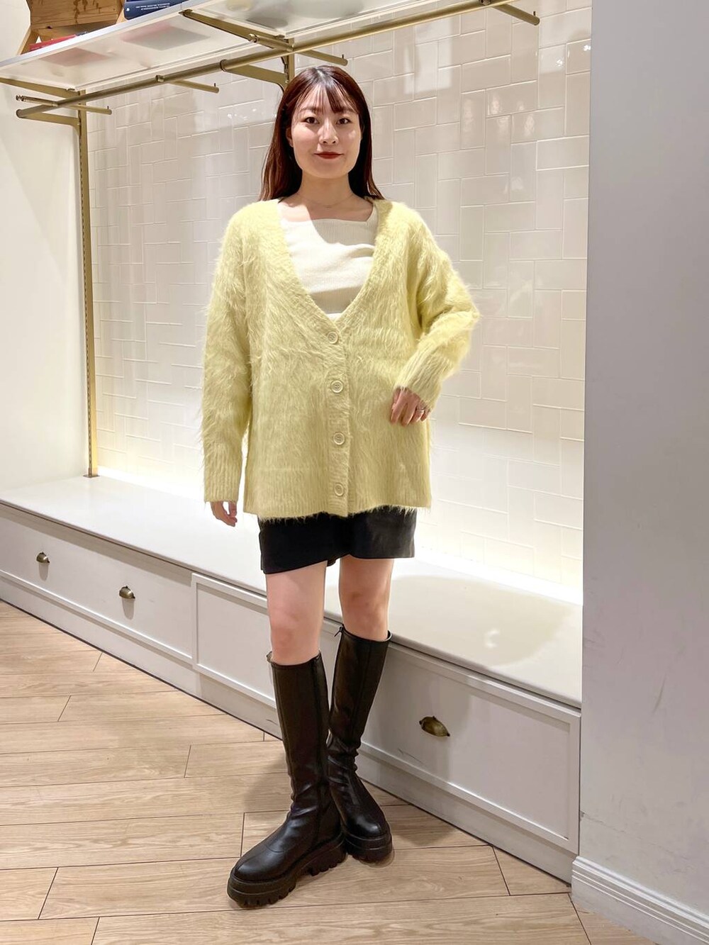 ホワイト系のニット/セーター、ブラック系のその他パンツ、ブラック系のブーツを着用したレディースの秋コーディネートの2枚目の写真