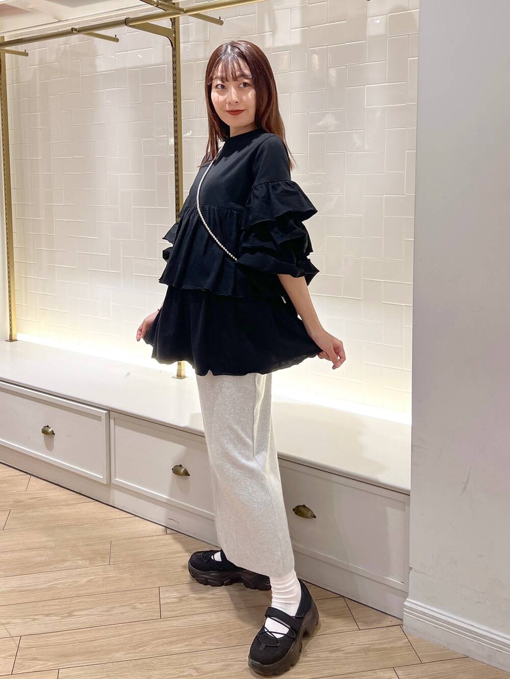 グレー系のスカート、ブラック系のスニーカー、ブラック系のワンピースを着用したレディースの秋コーディネートの3枚目の写真