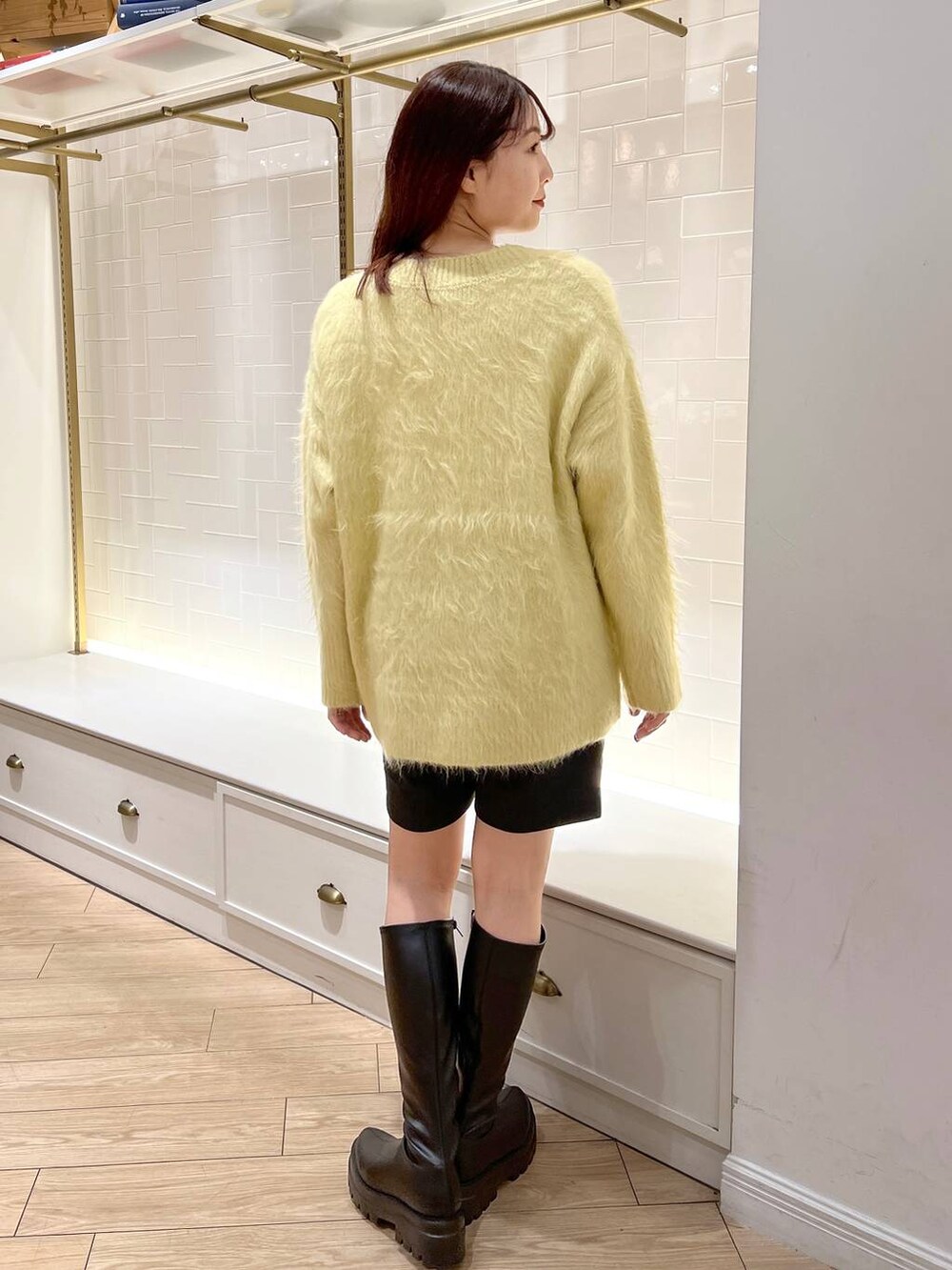 ホワイト系のニット/セーター、ブラック系のその他パンツ、ブラック系のブーツを着用したレディースの秋コーディネートの4枚目の写真