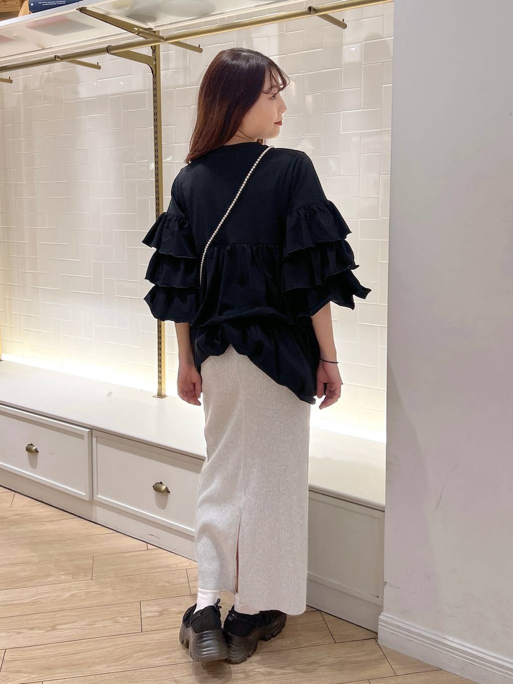 グレー系のスカート、ブラック系のスニーカー、ブラック系のワンピースを着用したレディースの秋コーディネートの4枚目の写真