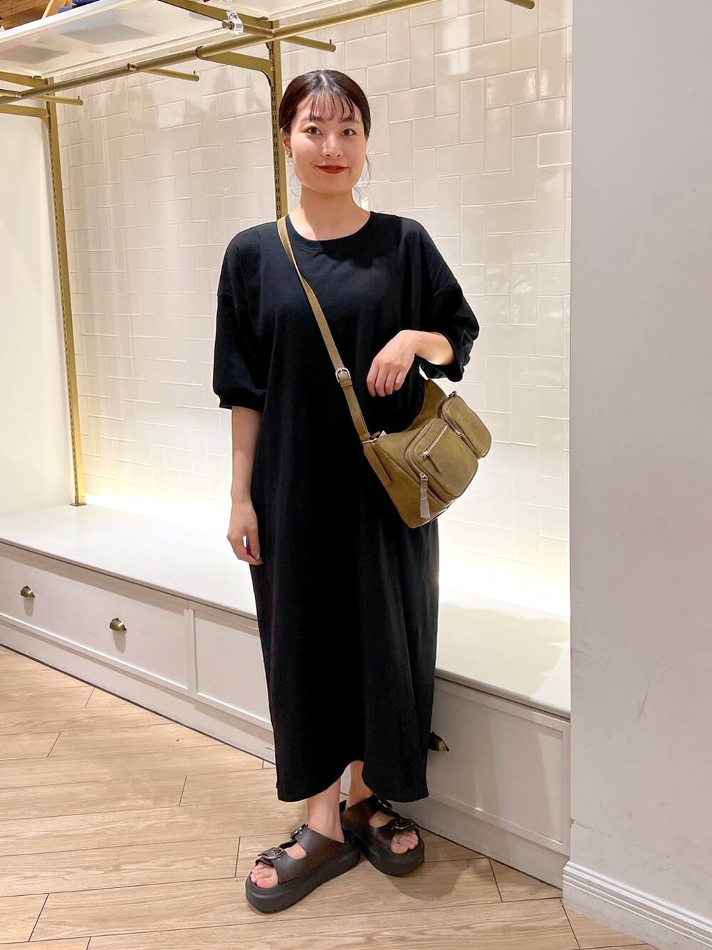 ブラウン系のサンダル、ブラック系のワンピース、ブラウン系のショルダーバッグを着用したレディースの夏コーディネートの2枚目の写真