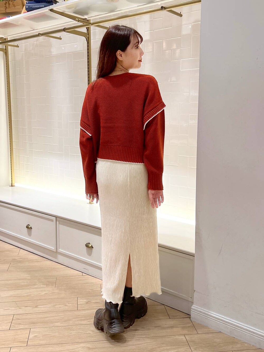 ブラック系のブーツ、レッド系のニット/セーター、ホワイト系のスカートを着用したレディースの秋コーディネートの4枚目の写真