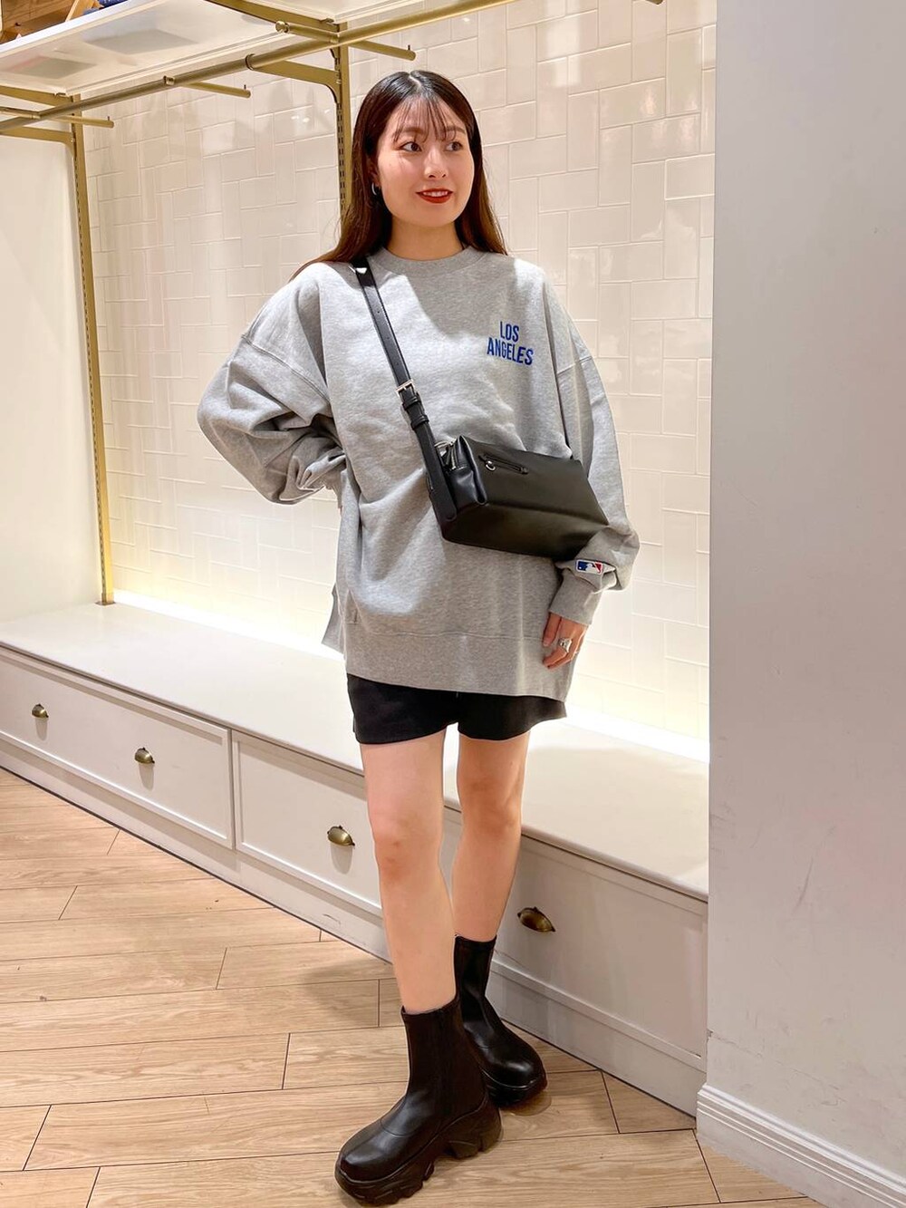 ブラック系のブーツ、グレー系のその他パンツ、ブラウン系のショルダーバッグを着用したレディースの秋コーディネートの3枚目の写真