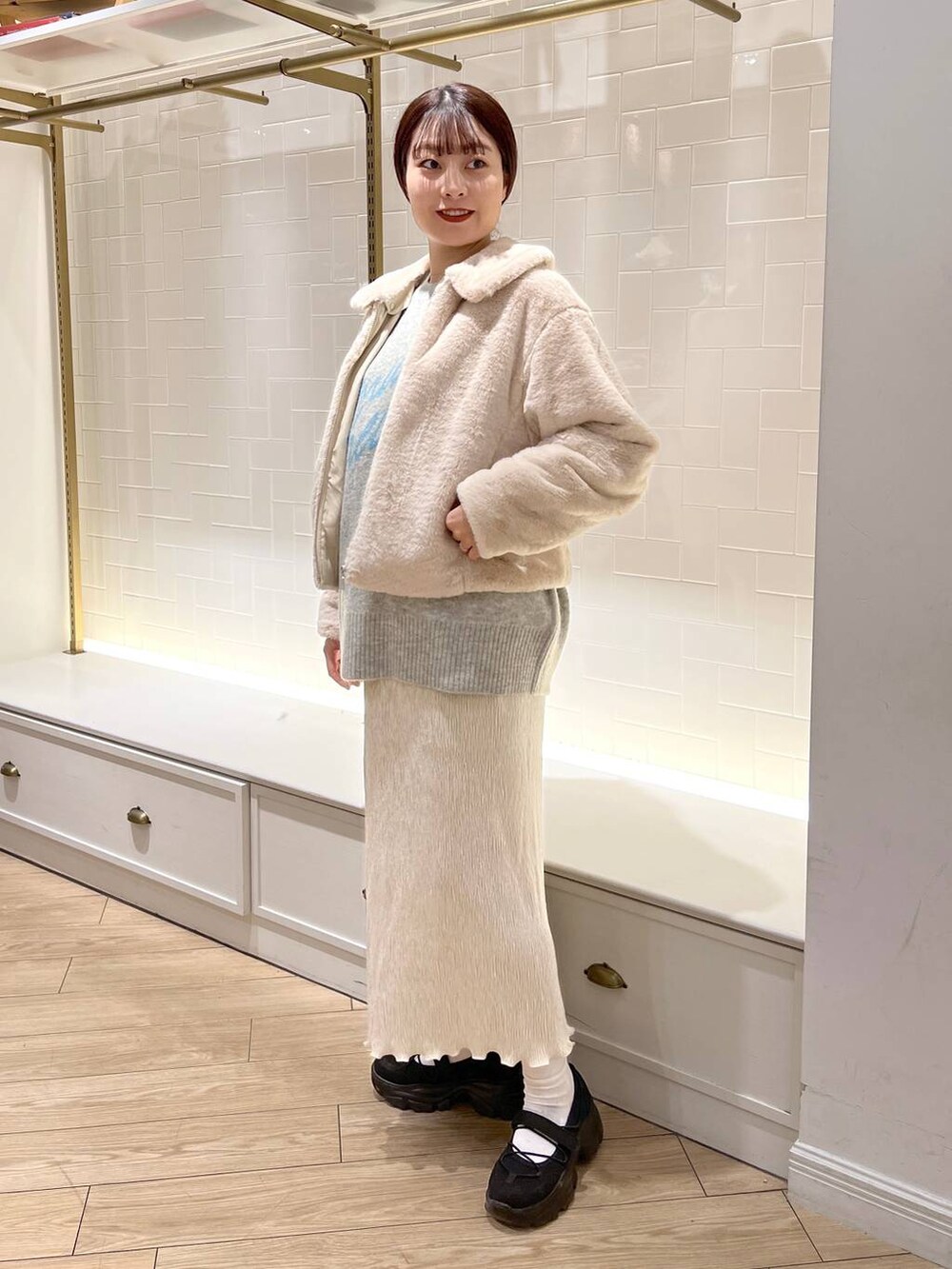 ホワイト系のブルゾン、ブラック系のスニーカー、ホワイト系のスカートを着用したレディースの秋コーディネートの3枚目の写真