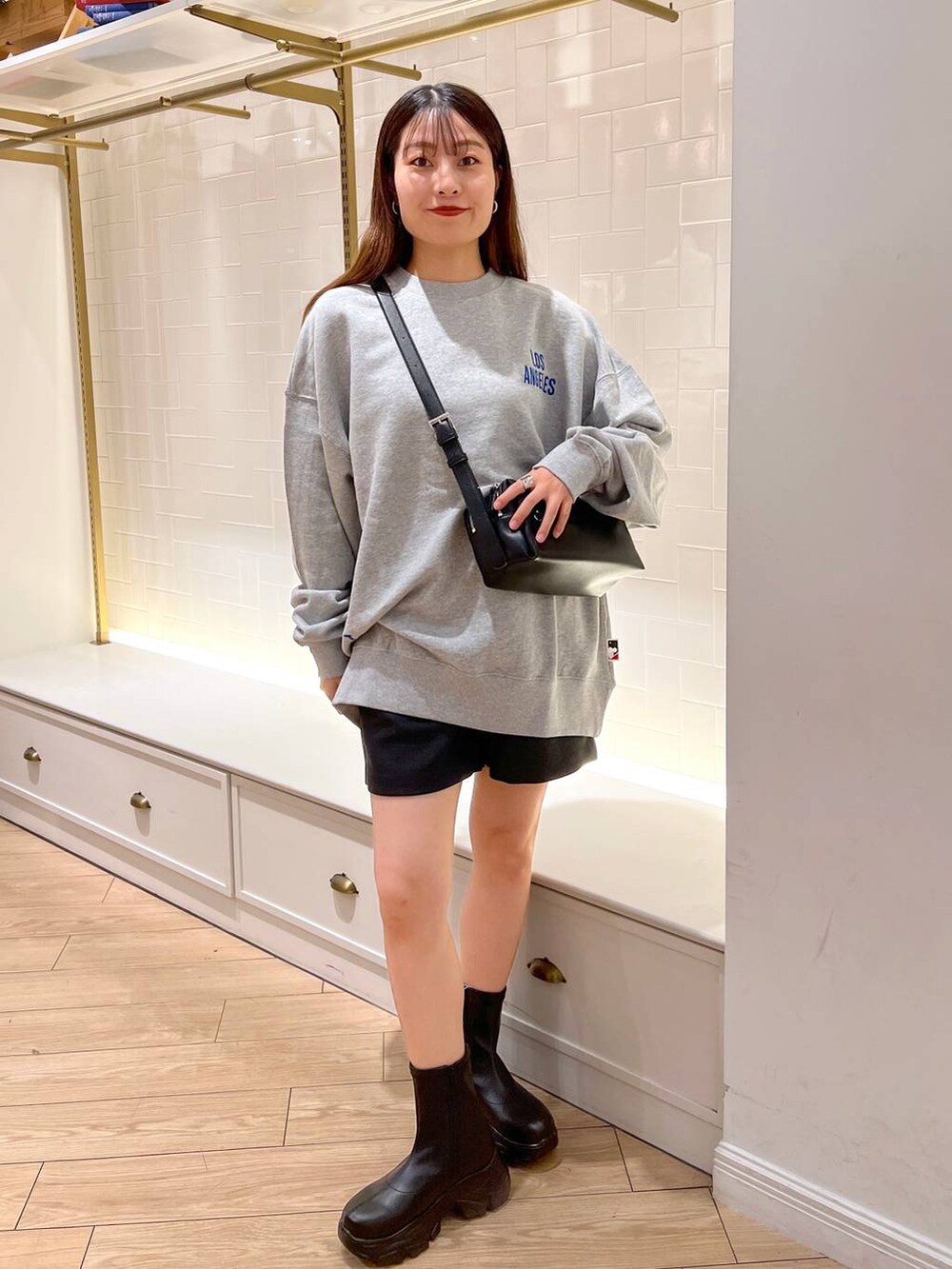 ブラック系のブーツ、グレー系のその他パンツ、ブラウン系のショルダーバッグを着用したレディースの秋コーディネートの2枚目の写真