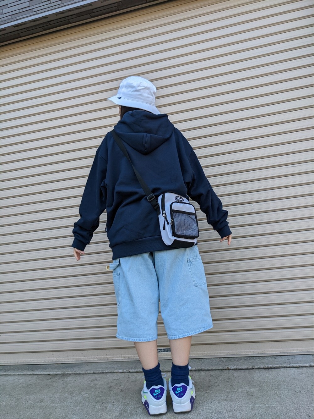 ブルー系のデニムパンツ、ホワイト系のスニーカー、ブルー系のパーカーを着用したレディースの冬コーディネートの3枚目の写真