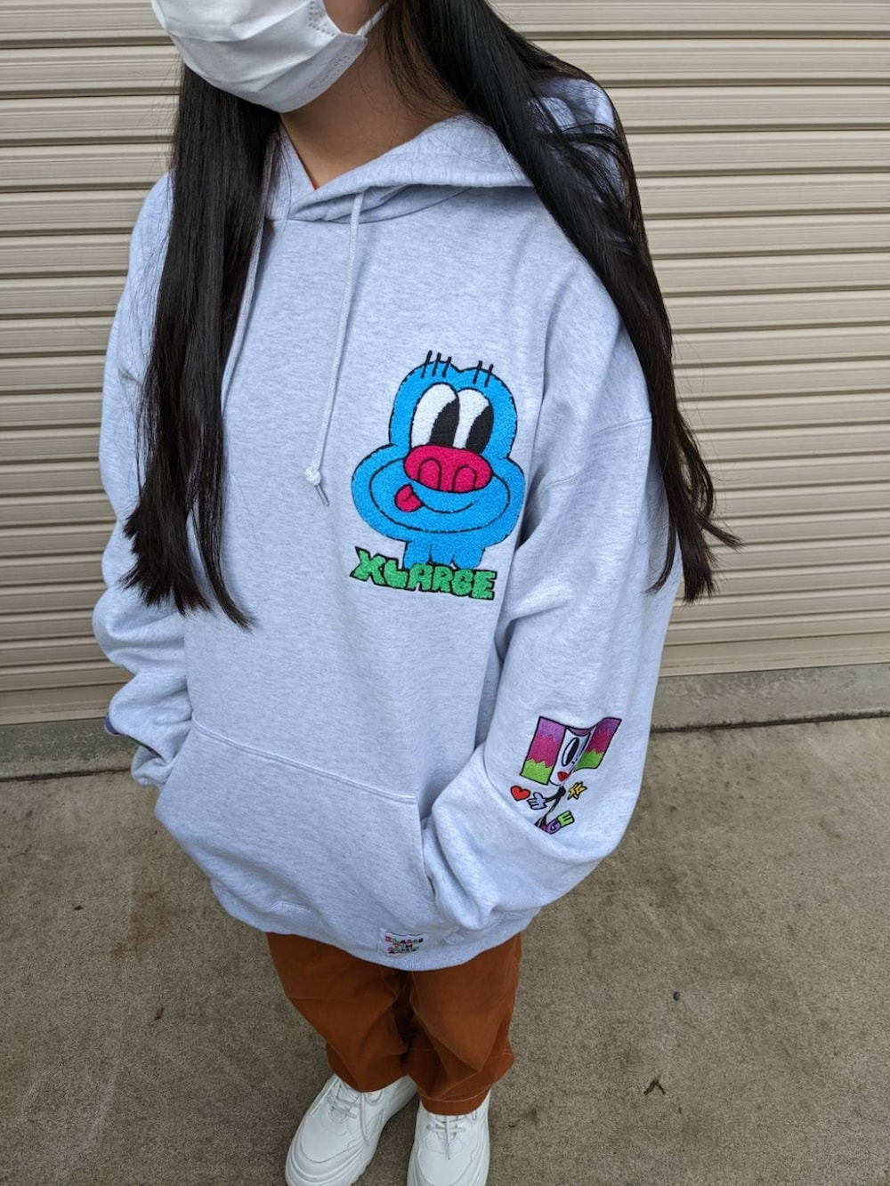 パープル系のベスト、グレー系のパーカー、ホワイト系のスニーカーを着用したレディースの冬コーディネートの2枚目の写真