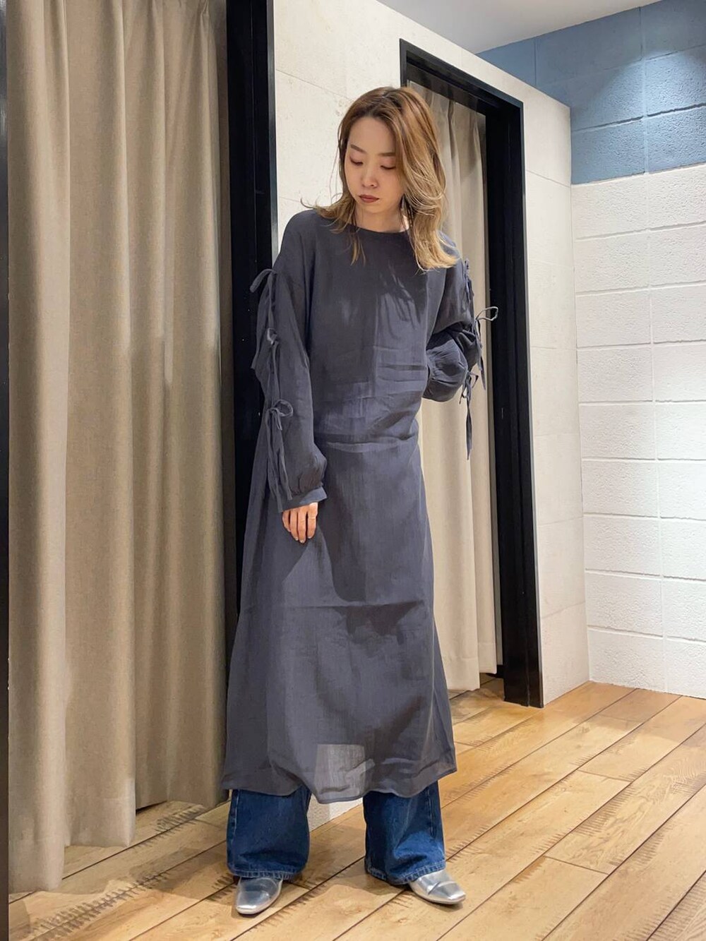 シルバー系のパンプス、ブルー系のデニムパンツ、グレー系のワンピースを着用したレディースの春コーディネートの2枚目の写真