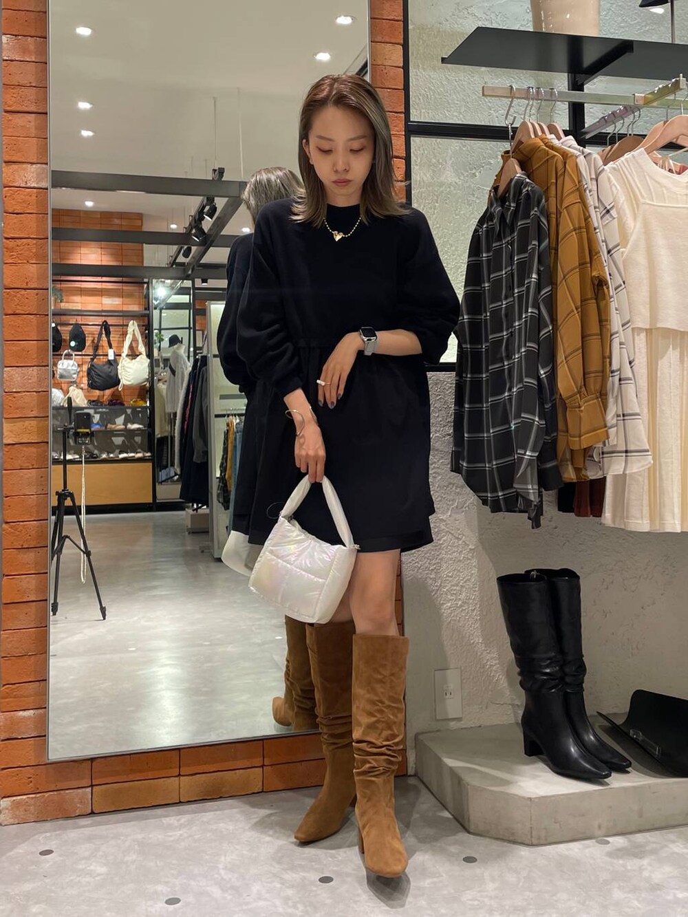 ブラウン系のブーツ、ブラック系のその他パンツ、ホワイト系のハンドバッグを着用したレディースの秋コーディネートの2枚目の写真