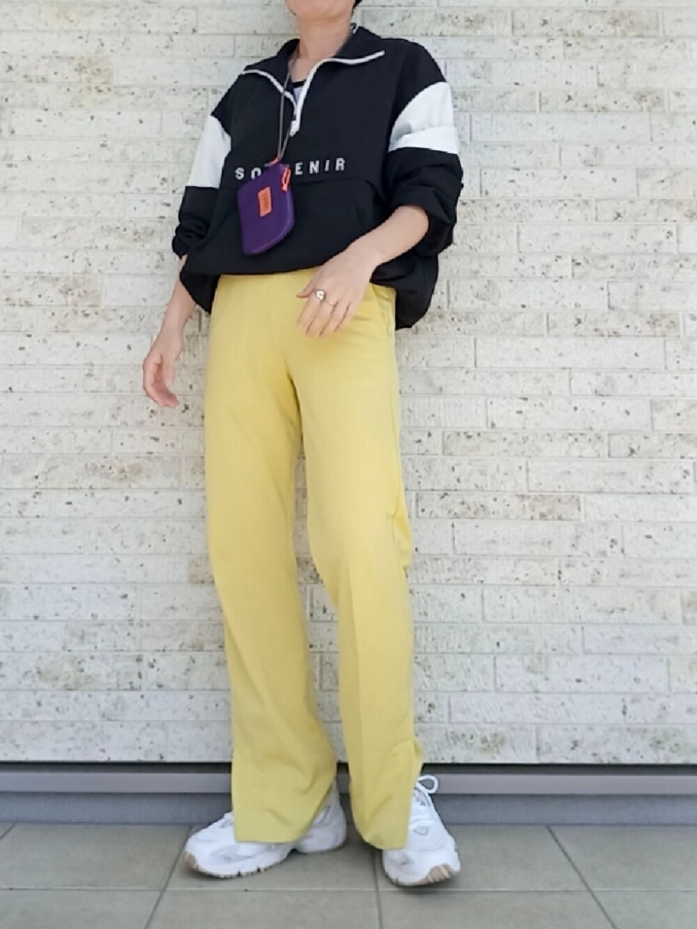 ブラック系のその他トップス、イエロー系のスラックス、ホワイト系のスニーカーを着用したレディースの春コーディネートの2枚目の写真