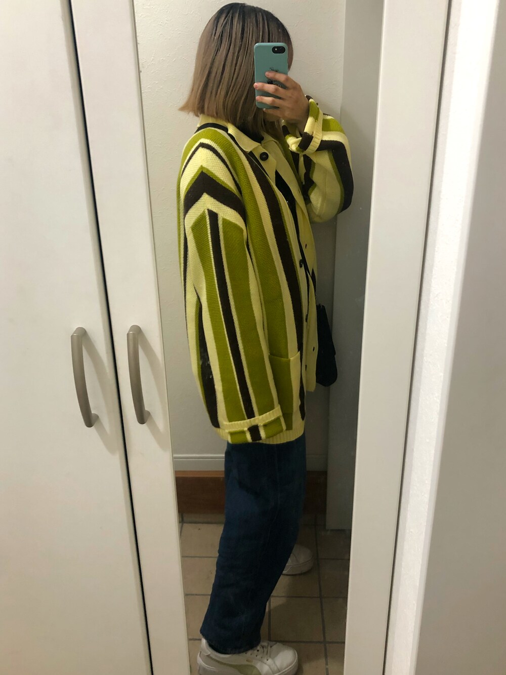 イエロー系のカーディガン/ボレロ、ブルー系のデニムパンツ、ホワイト系のスニーカーを着用したレディースの冬コーディネートの2枚目の写真