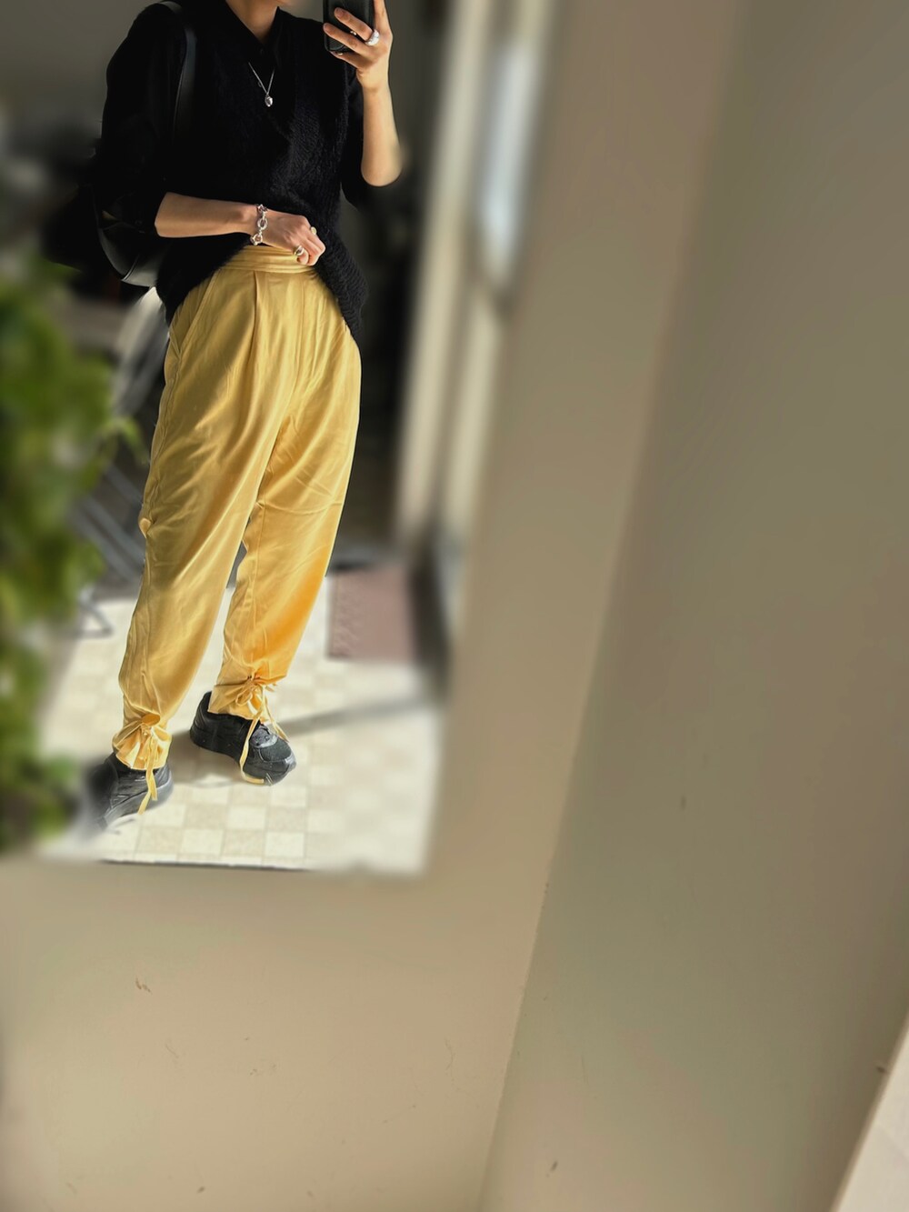 イエロー系のスラックス、ブラック系のシャツ/ブラウス、ブラック系のベストを着用したレディースの春コーディネートの2枚目の写真