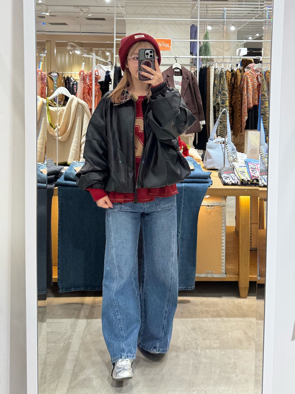 ブラック系のブルゾン、レッド系のTシャツ/カットソー、ブルー系のデニムパンツを着用したレディースの秋コーディネートの2枚目の写真