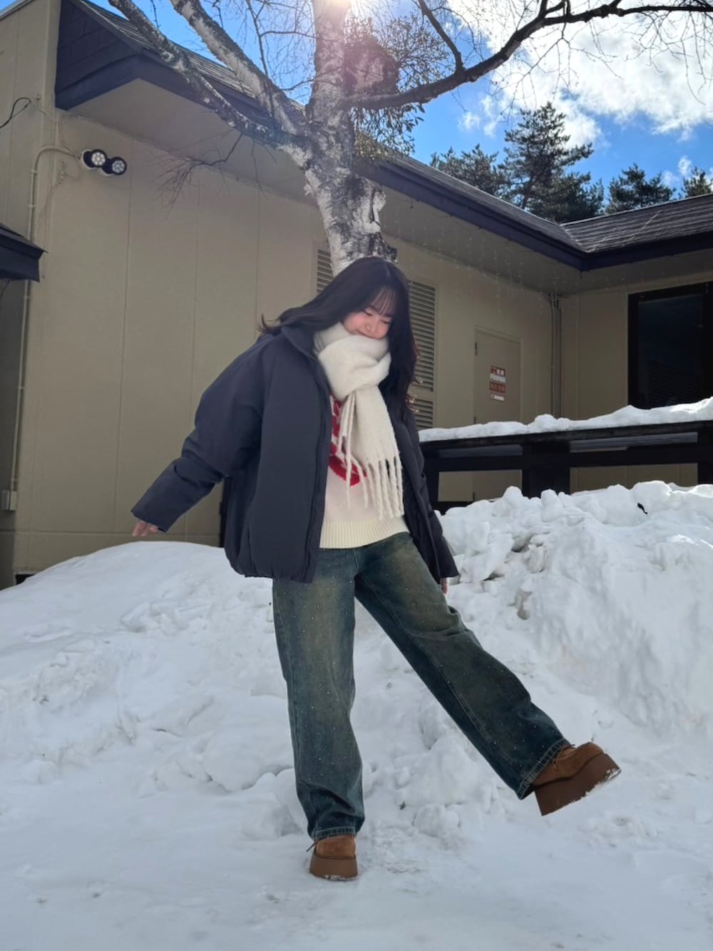 ベージュ系のブーツ、ブルー系のデニムパンツ、ブラック系のダウンジャケット/コートを着用したレディースの冬コーディネートの2枚目の写真