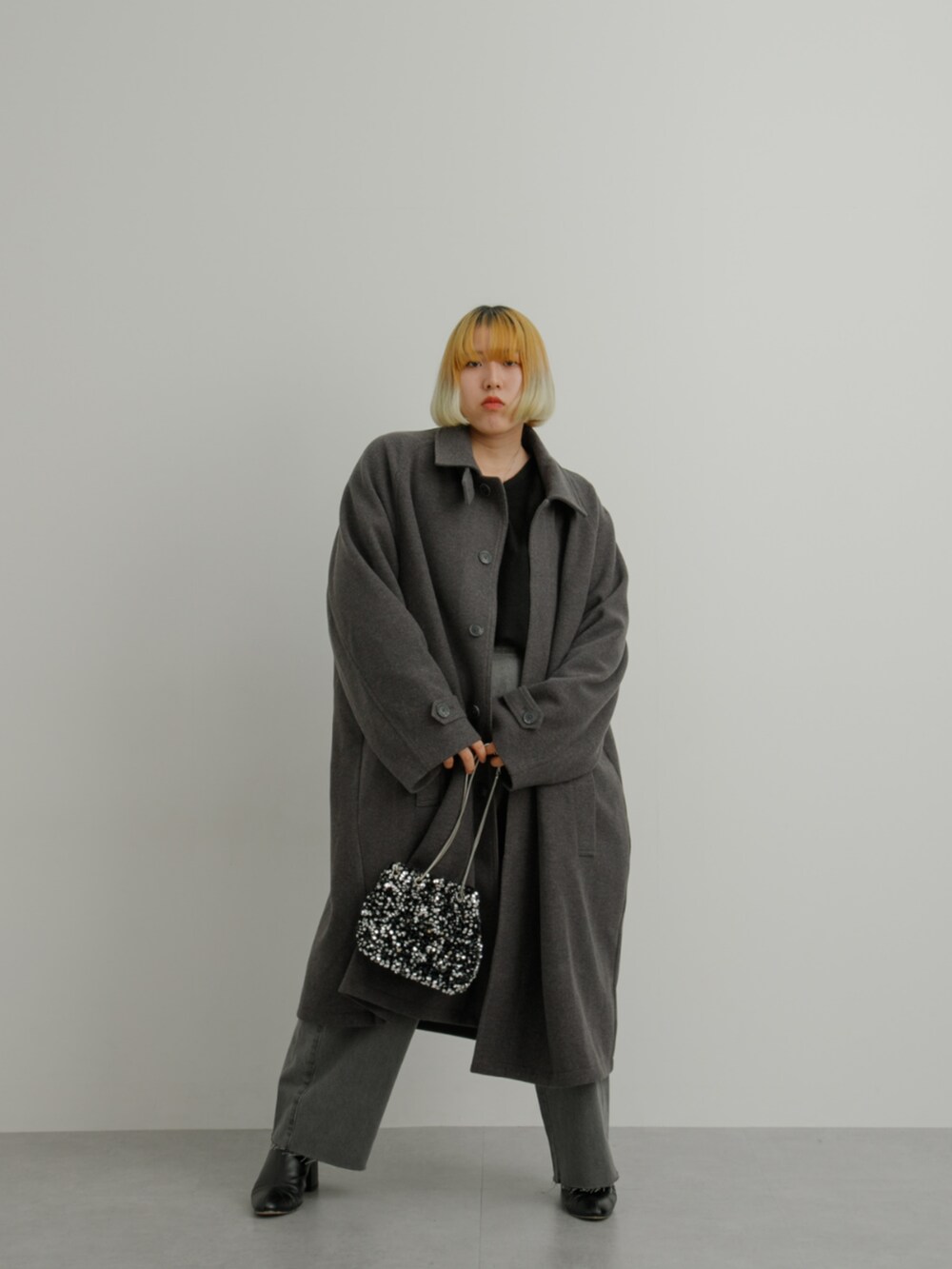 グレー系のジャケット/アウター、ブラック系のニット/セーター、グレー系のパンツを着用したレディースの冬コーディネートの2枚目の写真