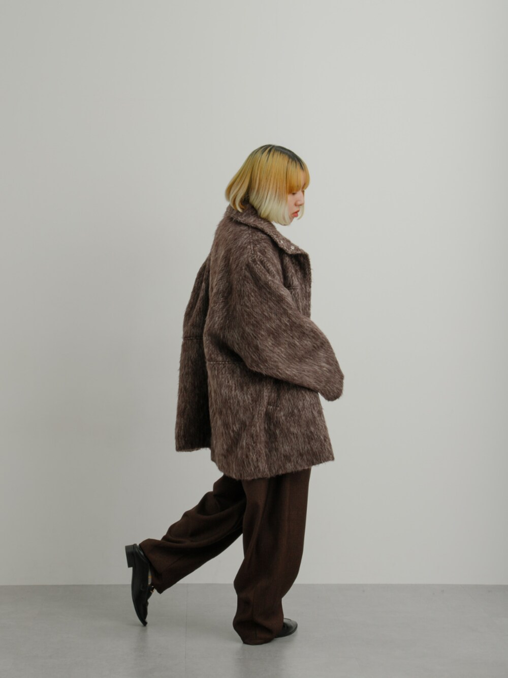 ブラウン系のジャケット/アウター、グレー系のニット/セーター、ブラウン系のスラックスを着用したレディースの冬コーディネートの2枚目の写真