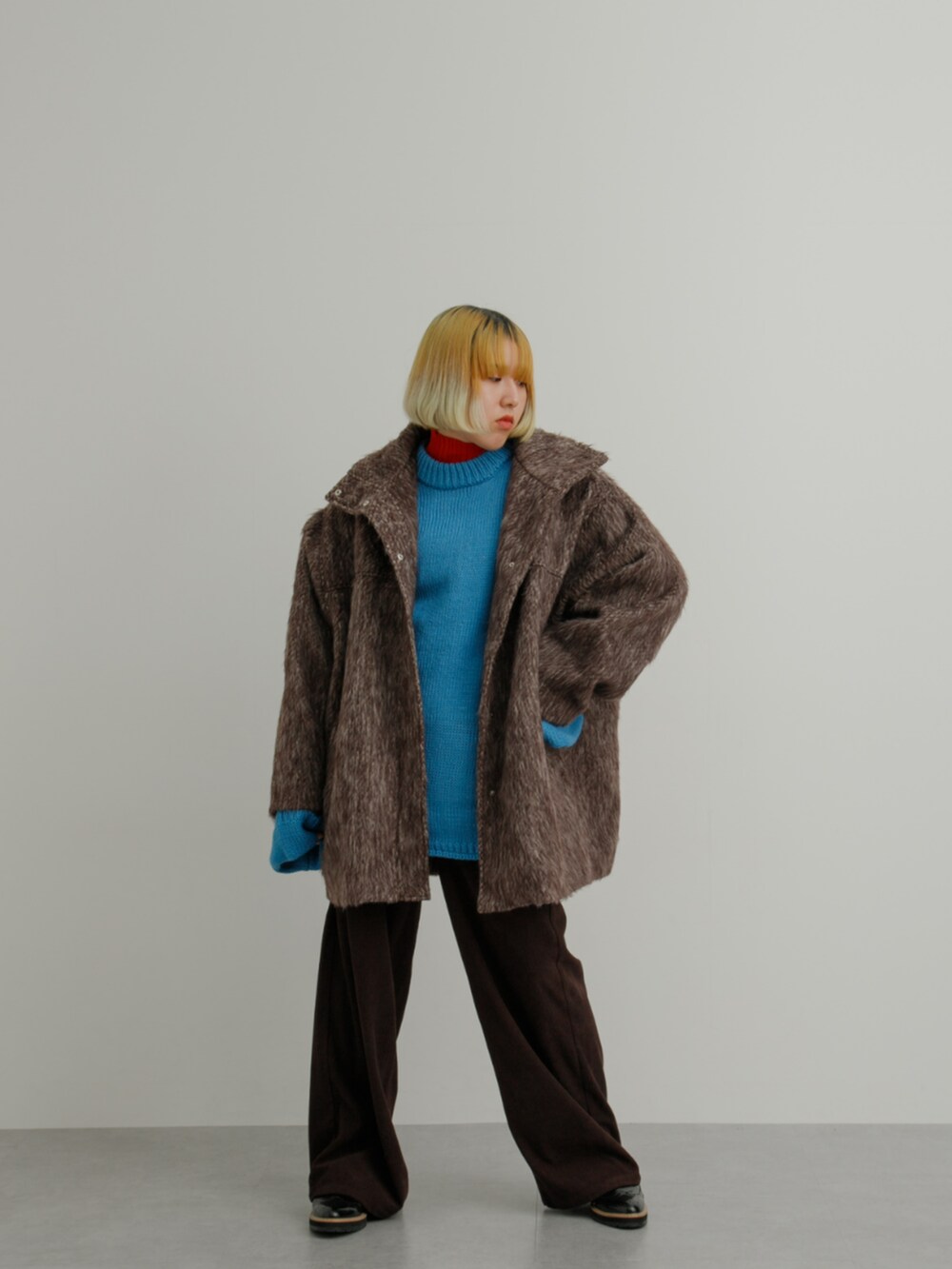 ブラウン系のジャケット/アウター、ブルー系のニット/セーター、レッド系のニット/セーターを着用したレディースの冬コーディネートの3枚目の写真