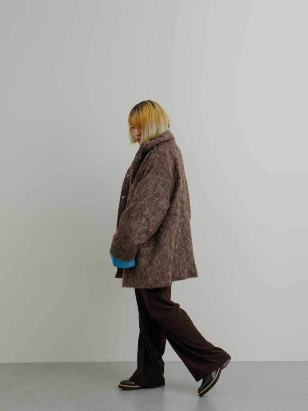 ブラウン系のジャケット/アウター、ブルー系のニット/セーター、レッド系のニット/セーターを着用したレディースの冬コーディネートの2枚目の写真