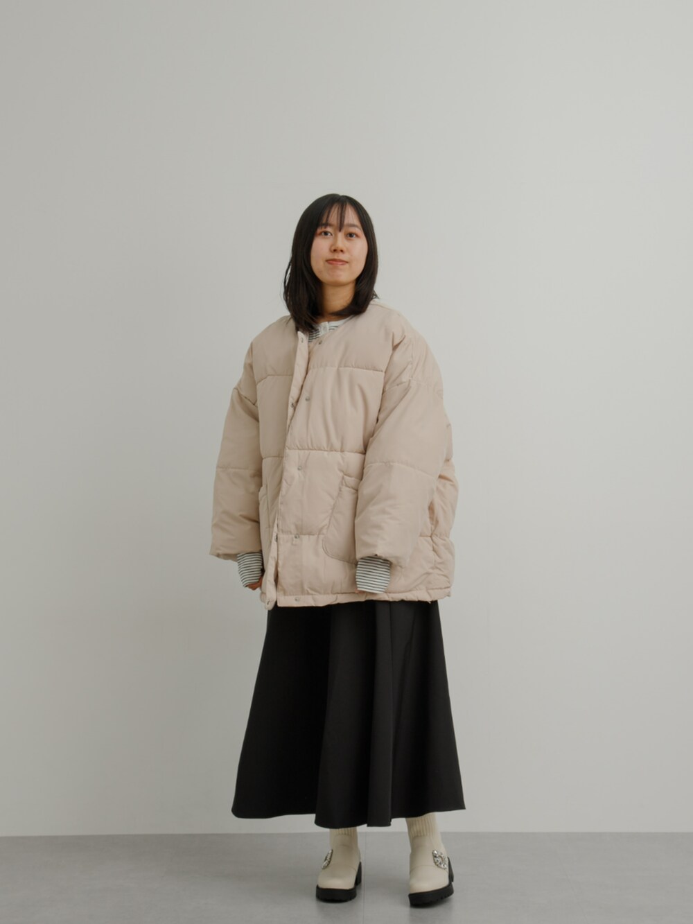 ベージュ系のジャケット/アウター、ホワイト系のTシャツ/カットソー、ブラック系のスカートを着用したレディースの冬コーディネートの2枚目の写真