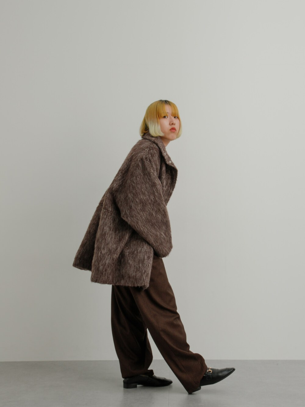 ブラウン系のジャケット/アウター、グレー系のニット/セーター、ブラウン系のスラックスを着用したレディースの冬コーディネートの3枚目の写真