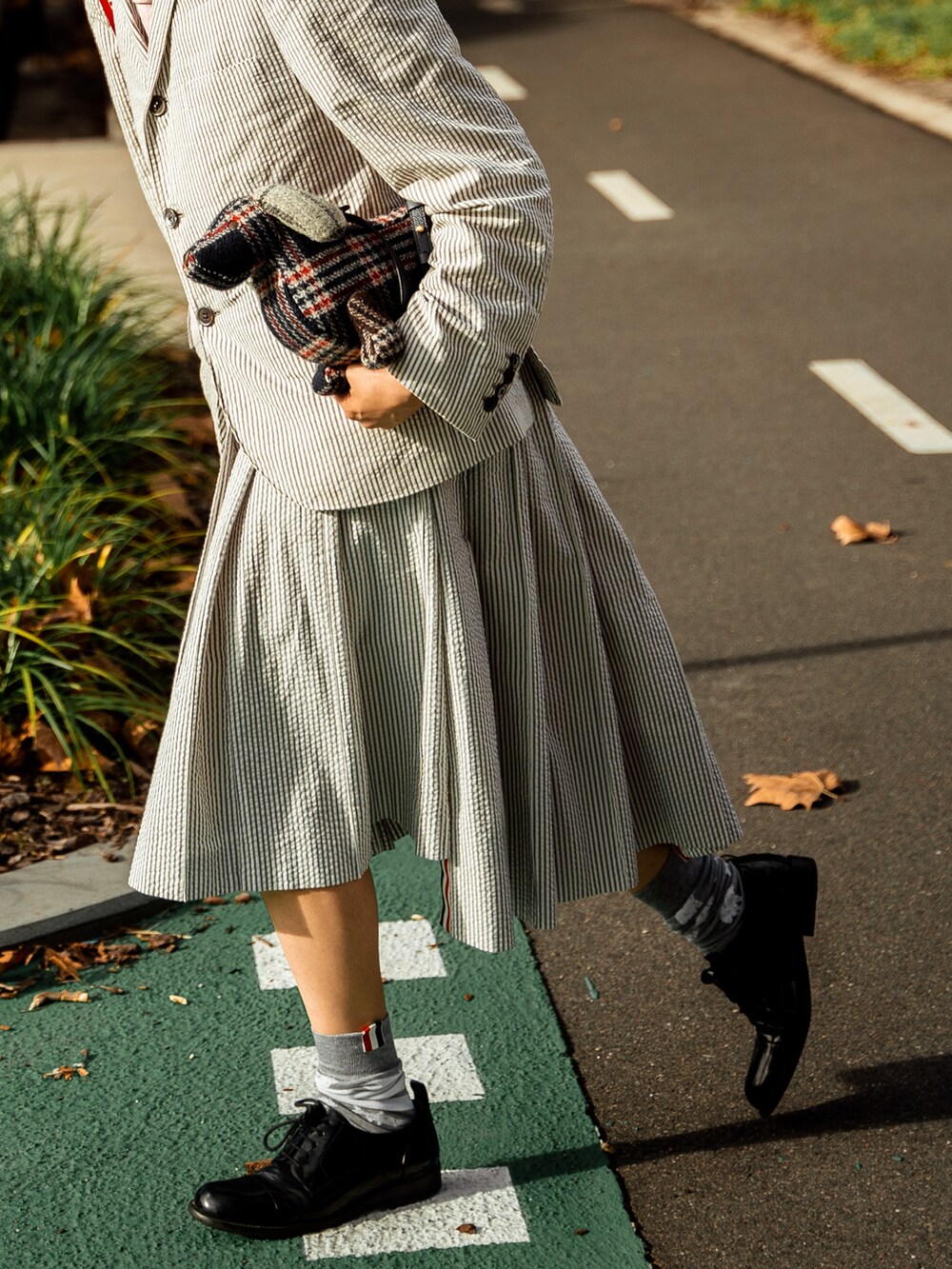 グレー系のテーラードジャケット、ブルー系のハンドバッグ、グレー系のスカートを着用したレディースの秋コーディネートの2枚目の写真