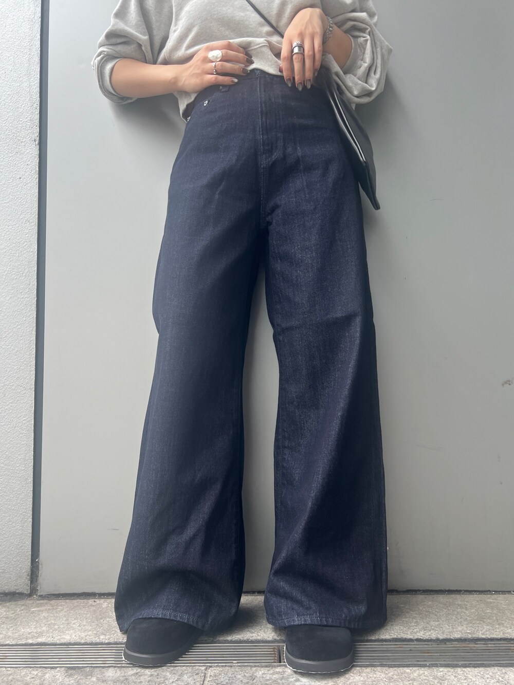 ブルー系のデニムパンツ、グレー系のスウェット、ブラック系のショルダーバッグを着用したレディースの秋コーディネートの5枚目の写真