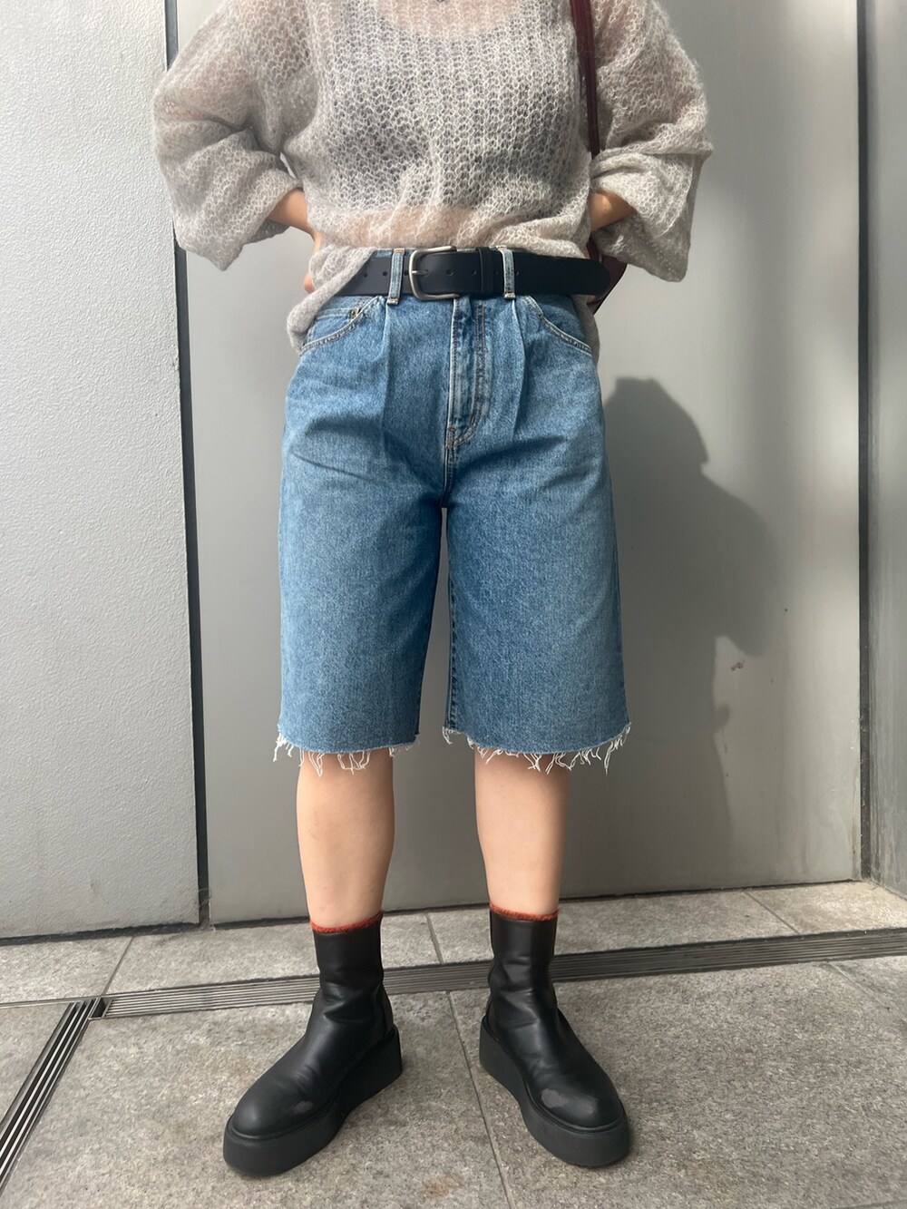 ブルー系のデニムパンツ、グレー系のニット/セーター、レッド系のハンドバッグを着用したレディースの秋コーディネートの5枚目の写真