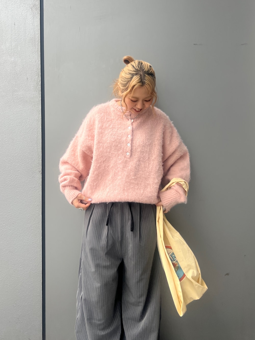 ピンク系のニット/セーター、イエロー系のトートバッグ、グレー系のその他パンツを着用したレディースの冬コーディネートの4枚目の写真