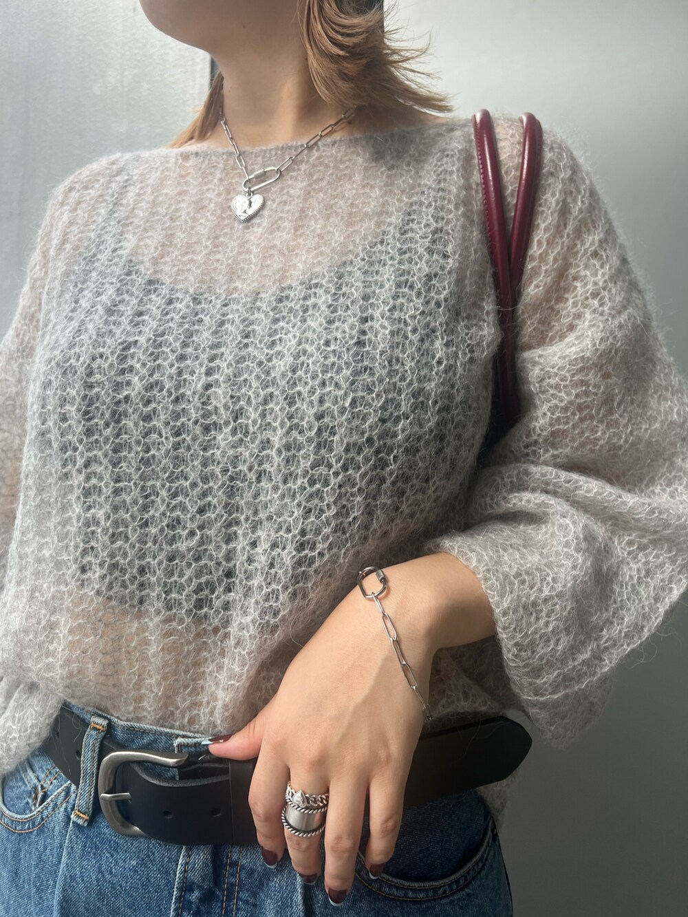 ブルー系のデニムパンツ、グレー系のニット/セーター、レッド系のハンドバッグを着用したレディースの秋コーディネートの6枚目の写真