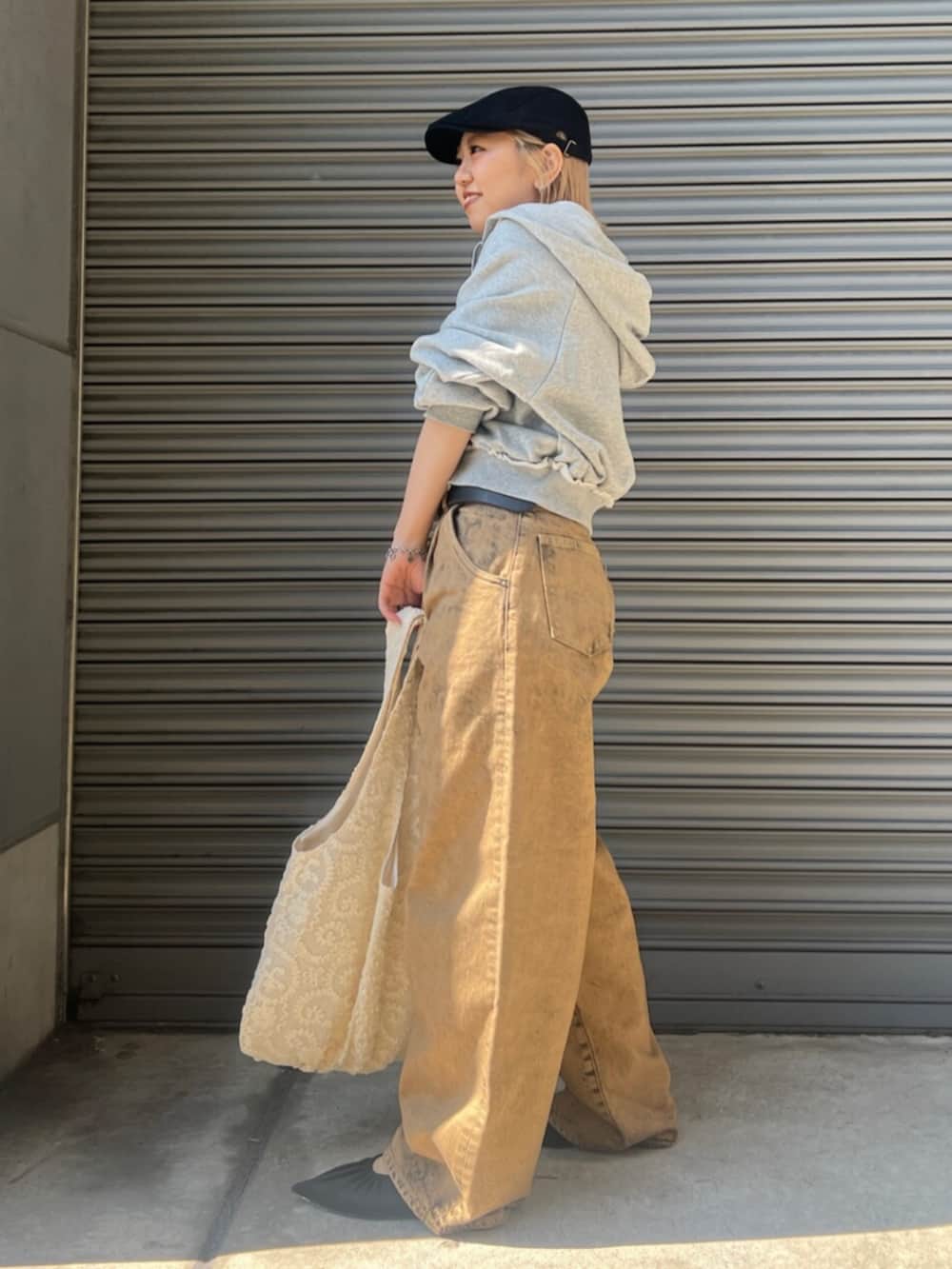 ブラック系のパンプス、ブラウン系のデニムパンツ、グレー系のパーカーを着用したレディースの春コーディネートの3枚目の写真