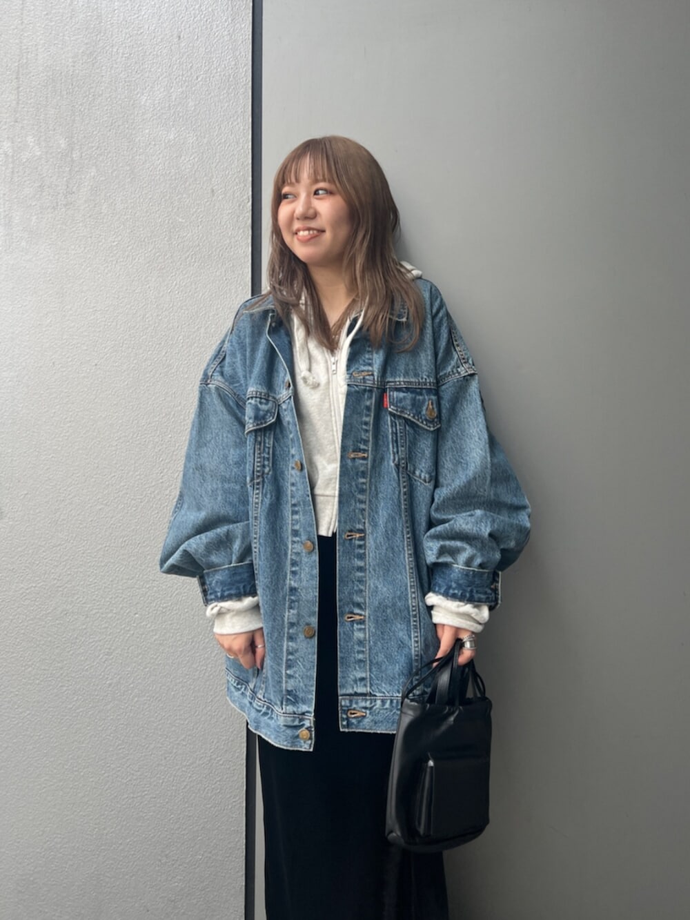 ホワイト系のパーカー、ブルー系のデニムジャケット、ブラック系のスカートを着用したレディースの秋コーディネートの6枚目の写真