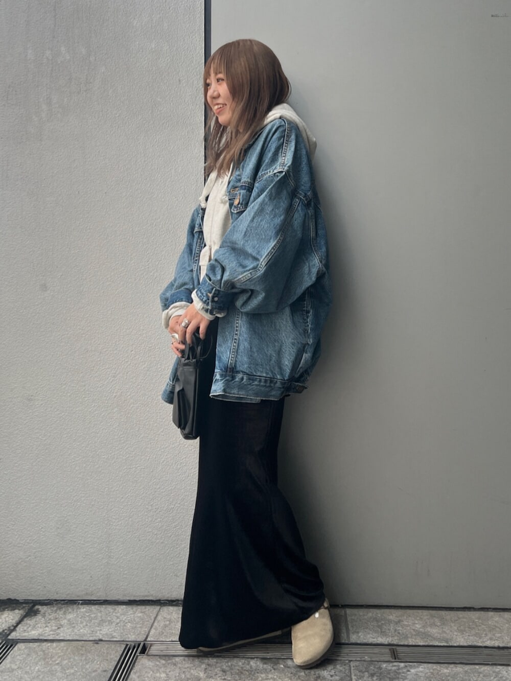 ホワイト系のパーカー、ブルー系のデニムジャケット、ブラック系のスカートを着用したレディースの秋コーディネートの2枚目の写真