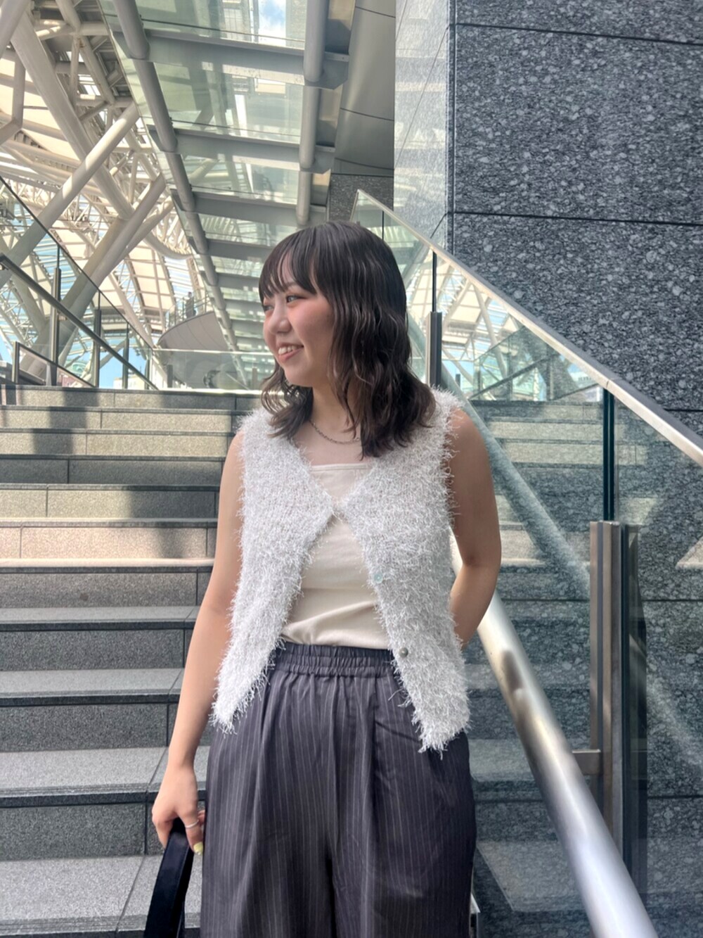 グレー系のその他パンツ、ホワイト系のベスト、ホワイト系のキャミソールを着用したレディースの春コーディネートの5枚目の写真