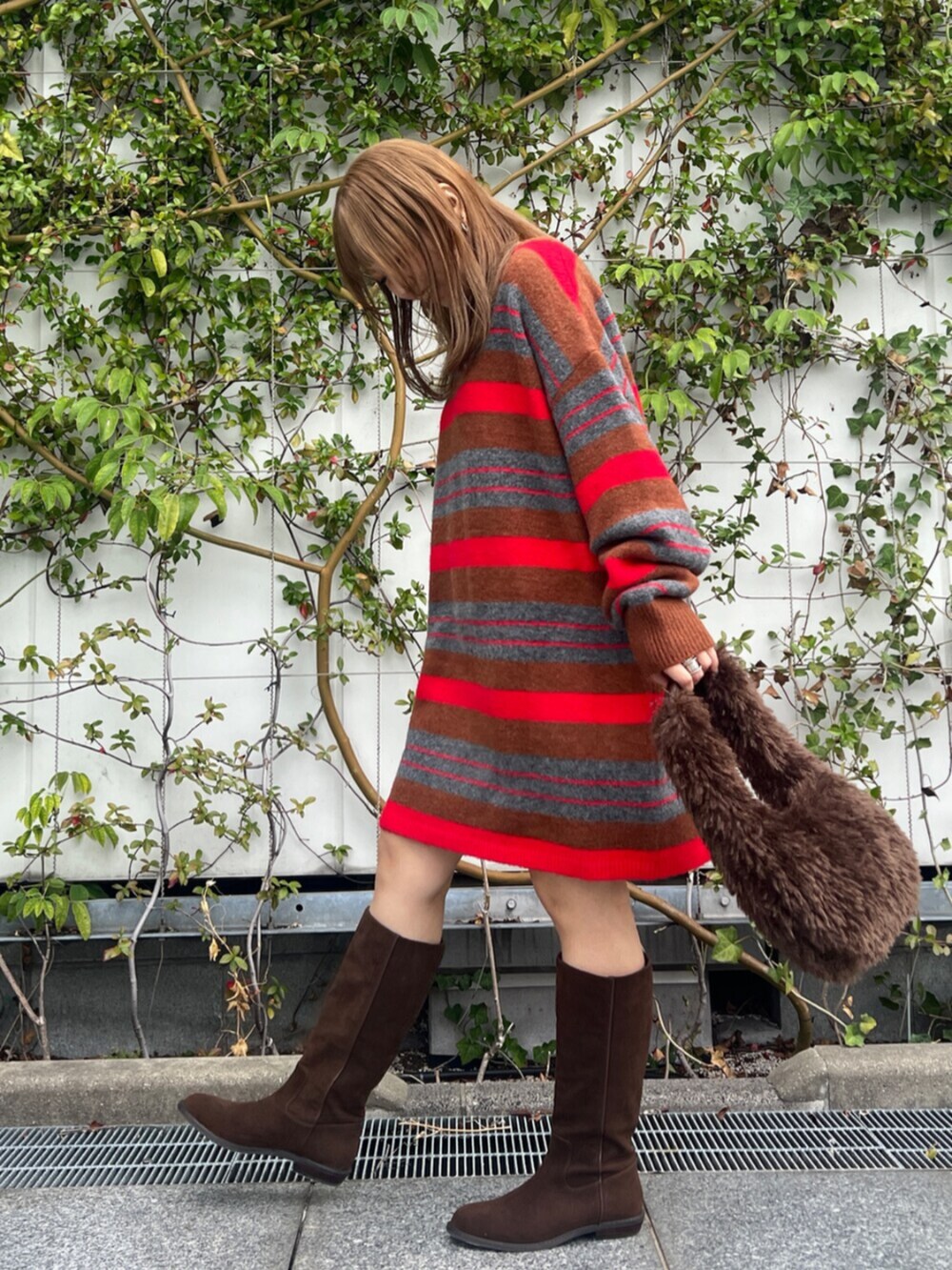 ブラウン系のハンドバッグ、レッド系のニット/セーター、ブラウン系のブーツを着用したレディースの秋コーディネートの2枚目の写真