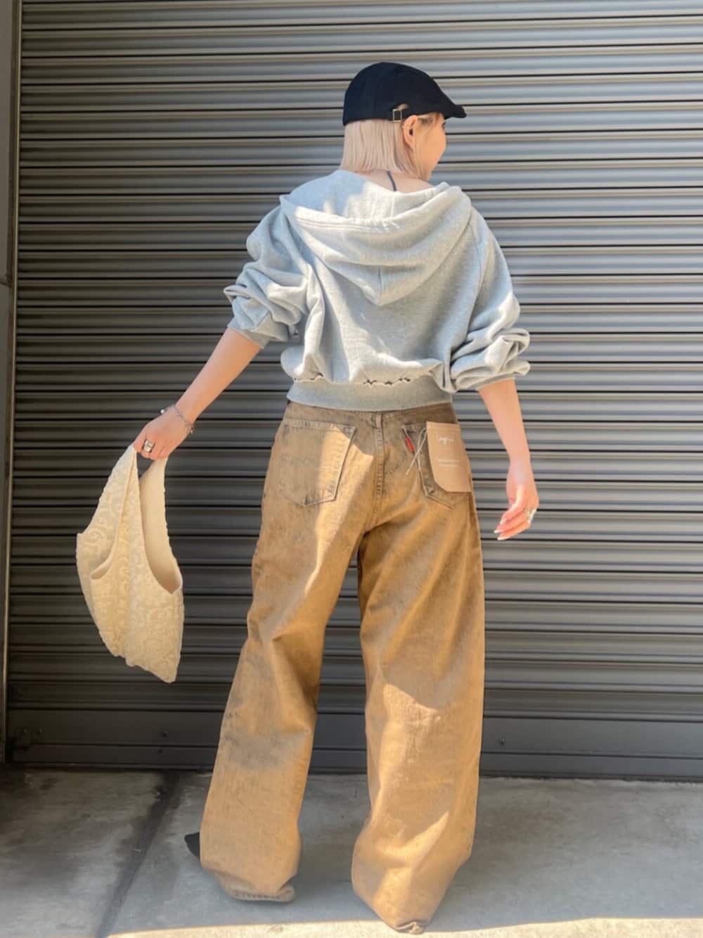 ブラック系のパンプス、ブラウン系のデニムパンツ、グレー系のパーカーを着用したレディースの春コーディネートの4枚目の写真