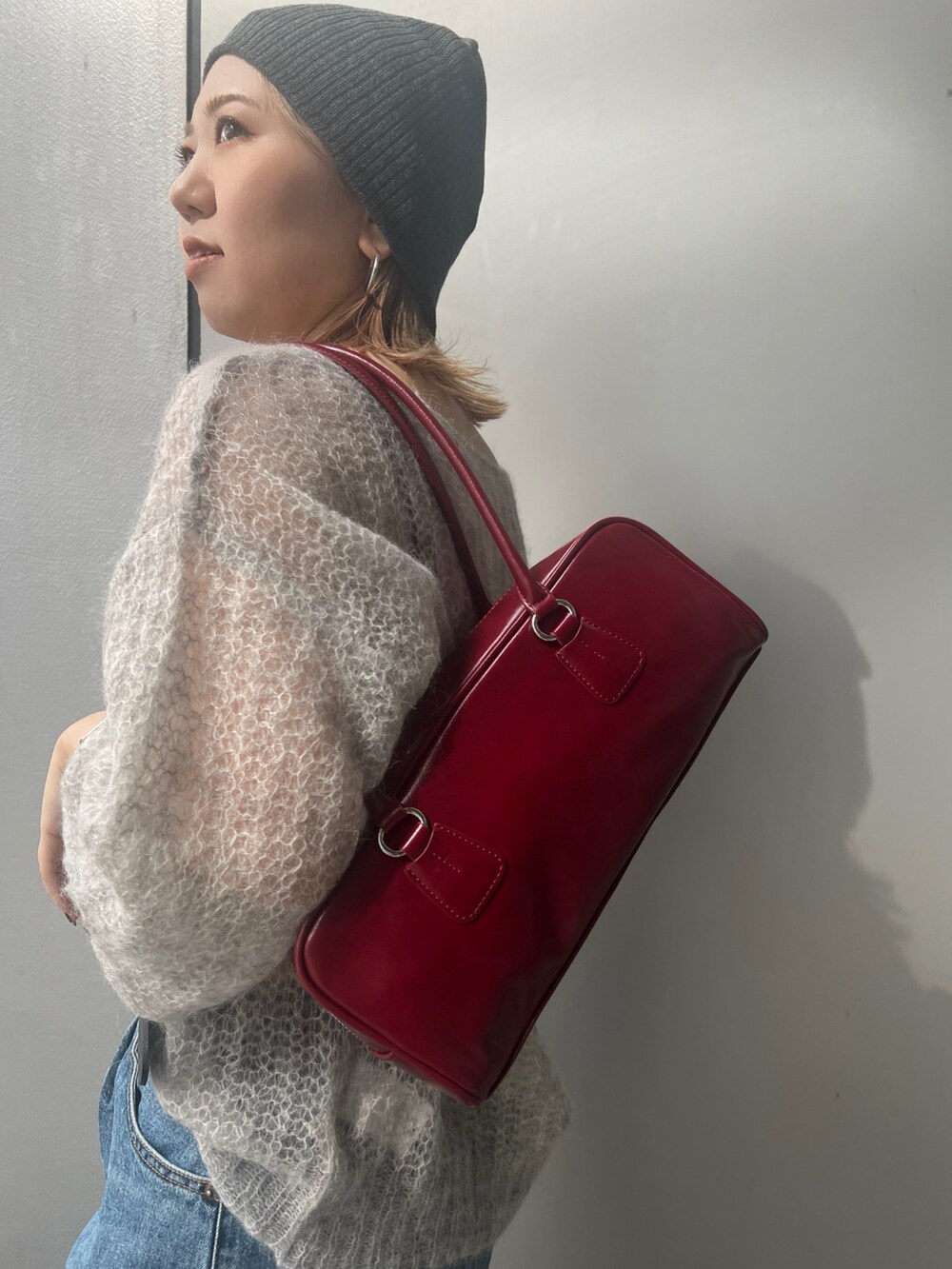 ブルー系のデニムパンツ、グレー系のニット/セーター、レッド系のハンドバッグを着用したレディースの秋コーディネートの7枚目の写真