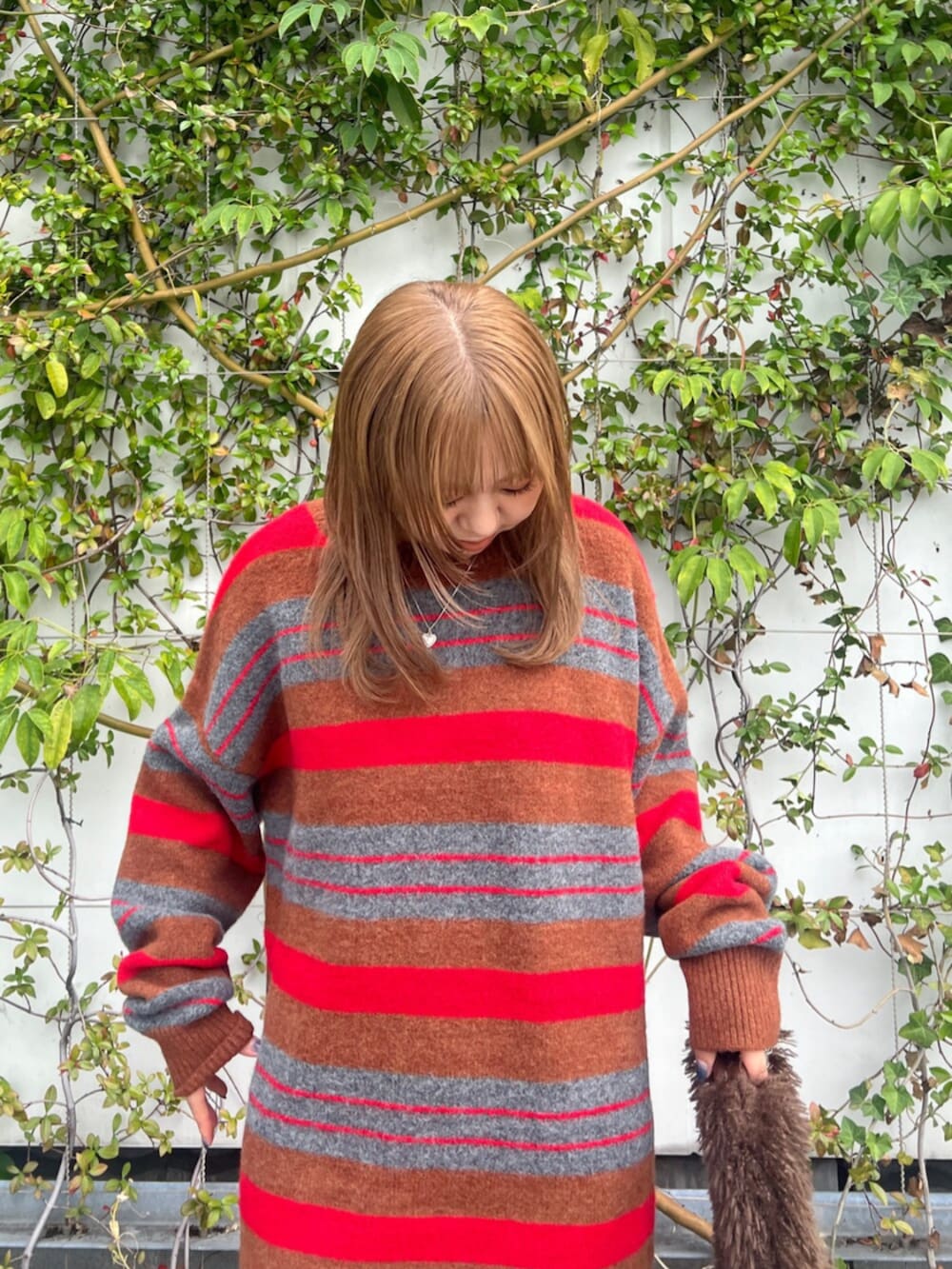 ブラウン系のハンドバッグ、レッド系のニット/セーター、ブラウン系のブーツを着用したレディースの秋コーディネートの5枚目の写真